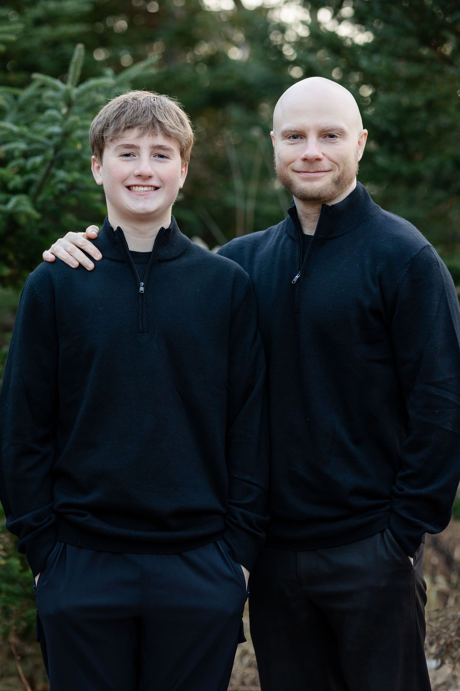 Two people in matching black sweaters share candid moments during an outdoor photo session.