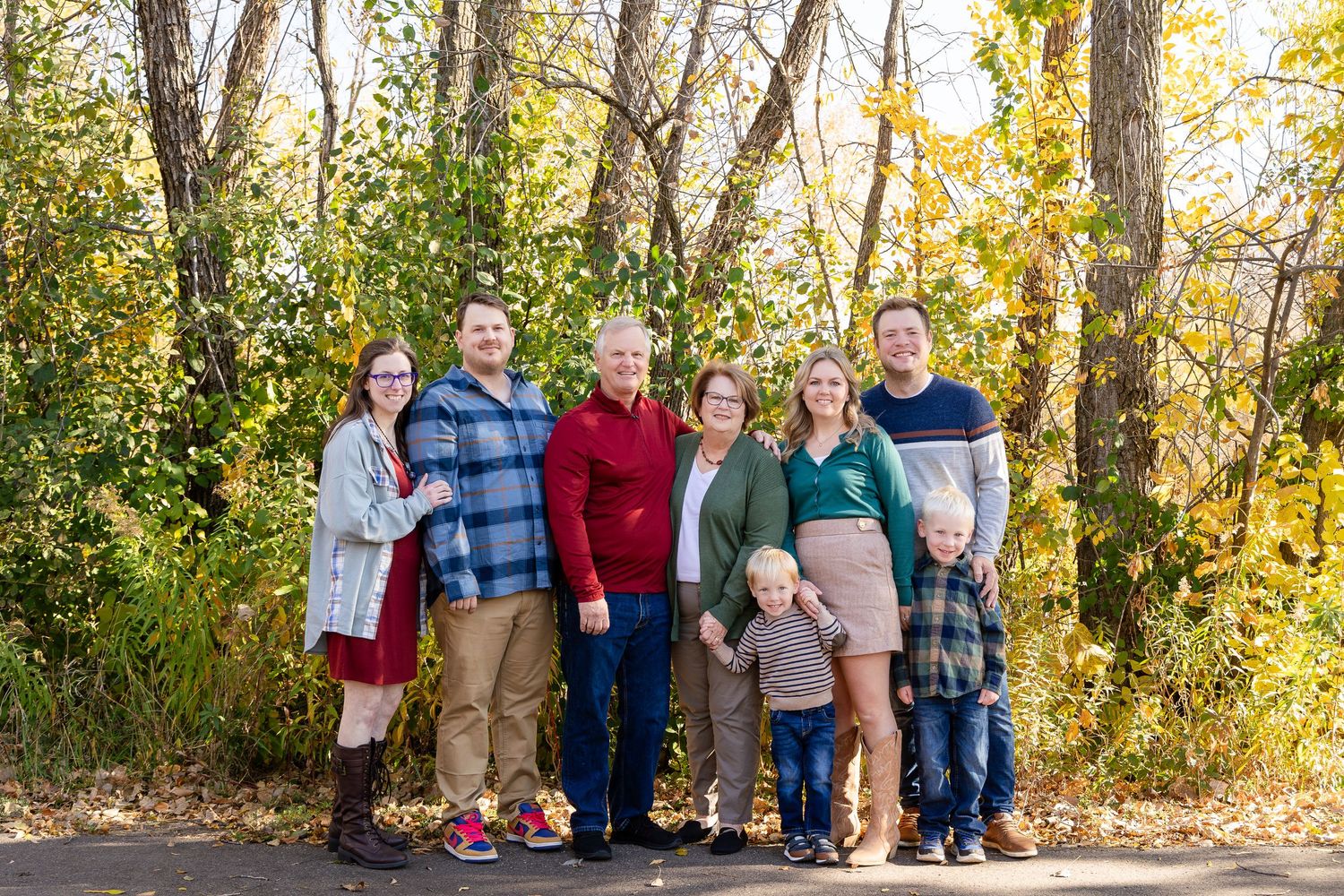 Extended family gathering outdoors among autumn trees and natural lighting.