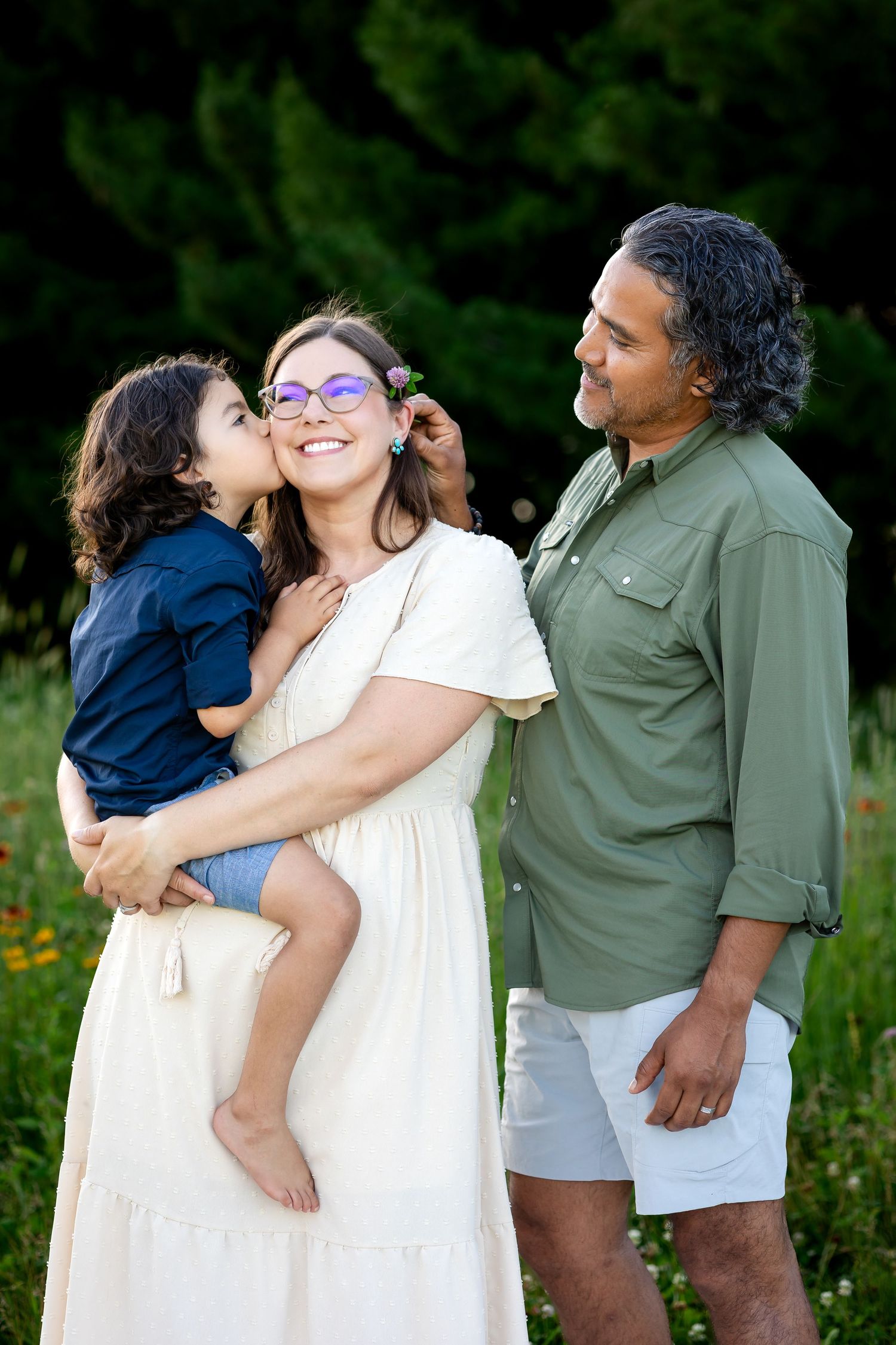 Family enjoying candid moments together outdoors in a natural setting with wildflowers.