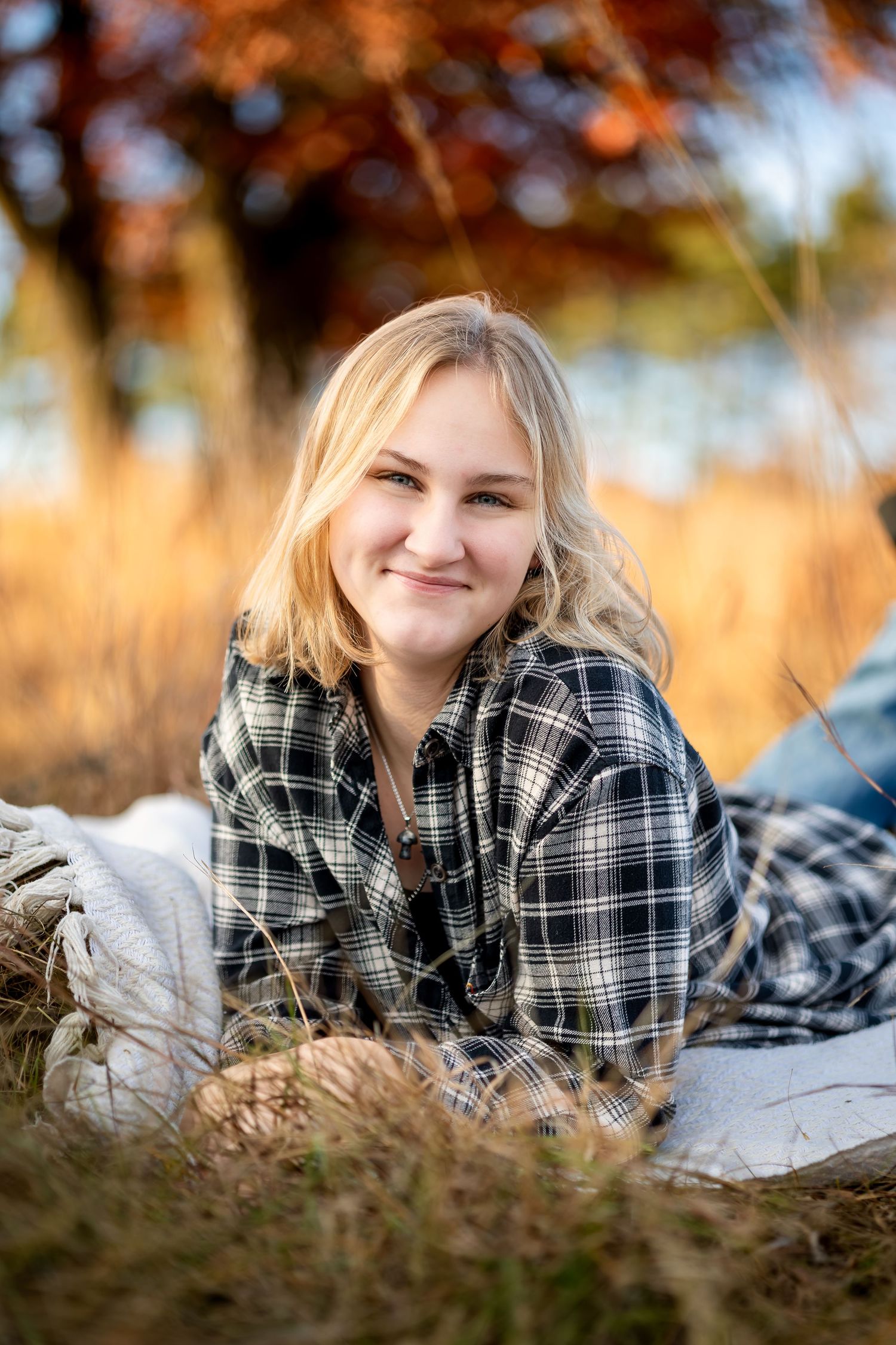 A series of outdoor portrait shots in autumn showing someone laying in tall grass wearing a plaid flannel shirt.