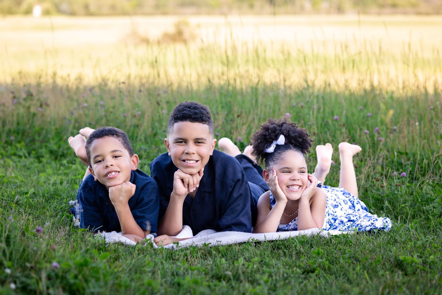 Group lying casually on grass during an outdoor summer photoshoot.