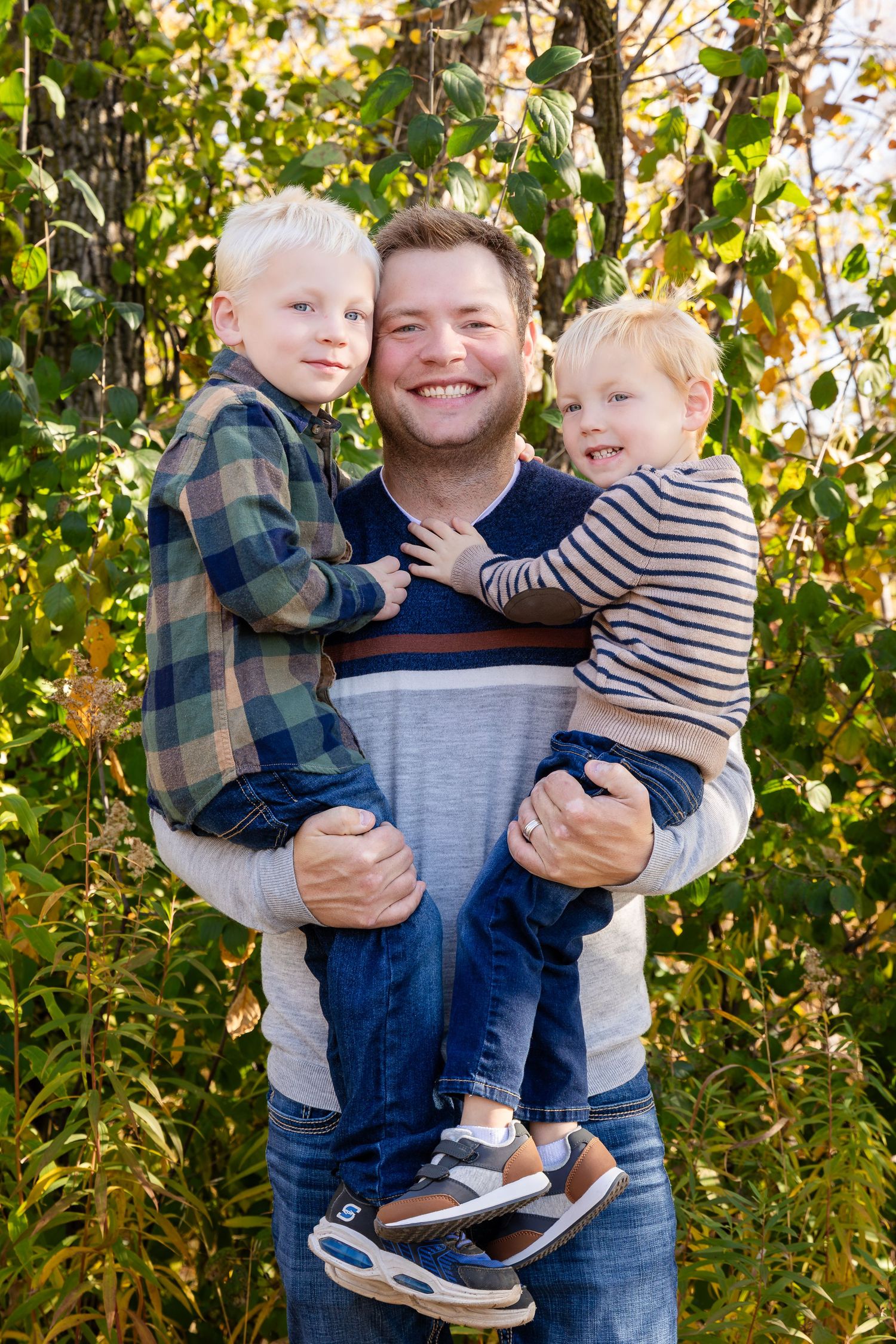 Playful sibling interaction in outdoor setting with green foliage background.