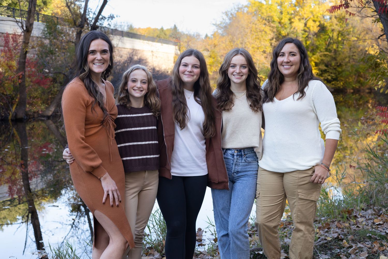 Friends gathered for outdoor photos with autumn colors and water in background.