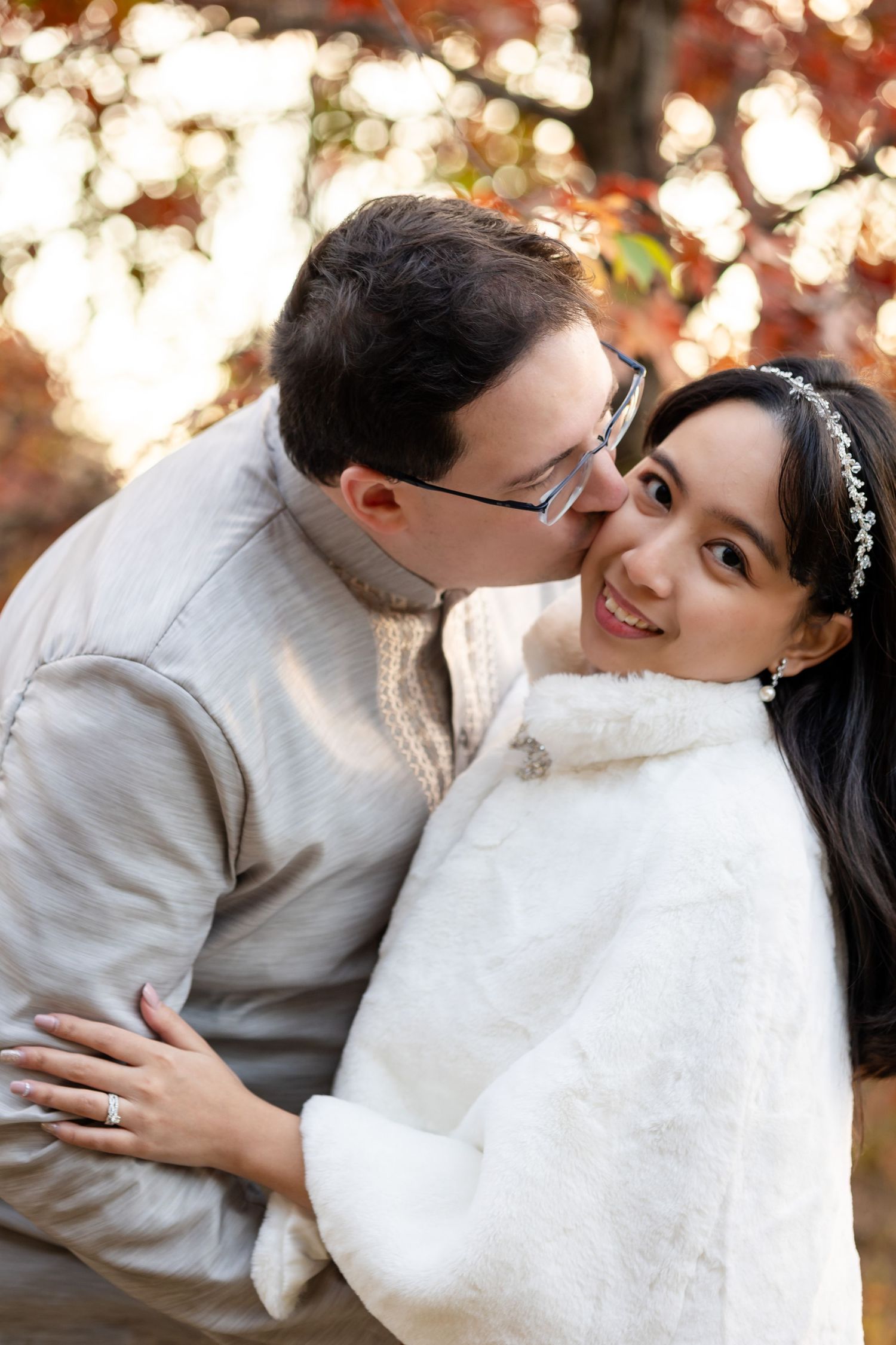A romantic couple embraces with autumn bokeh lights in the background.