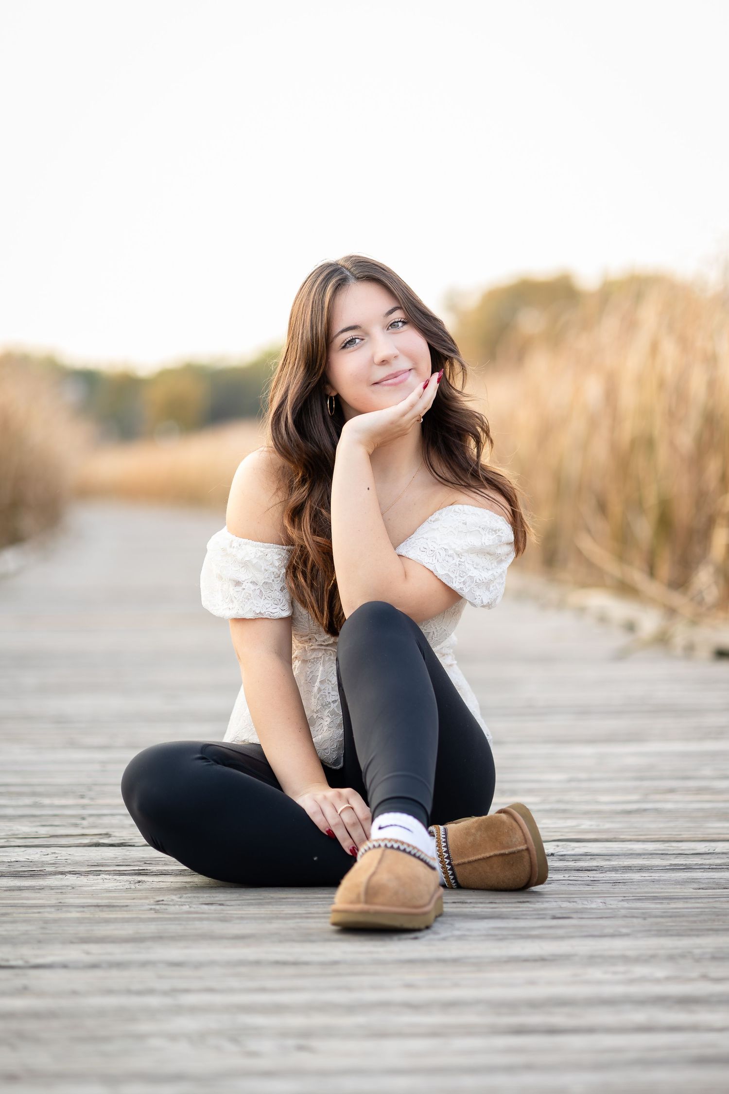 Casual portrait on wooden boardwalk wearing boots and black pants.