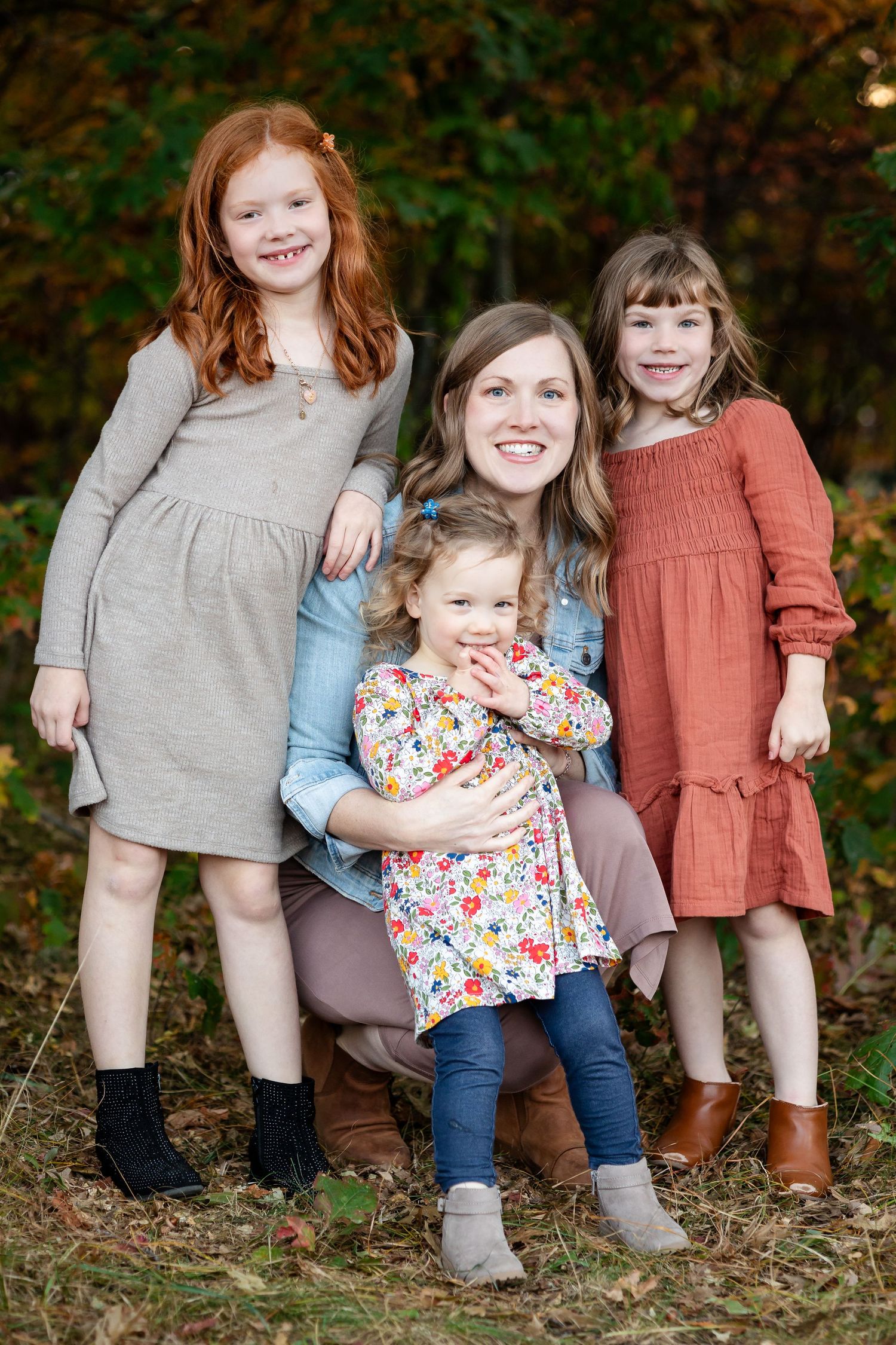 Candid family portrait showing playful interaction while sitting together on fallen leaves.