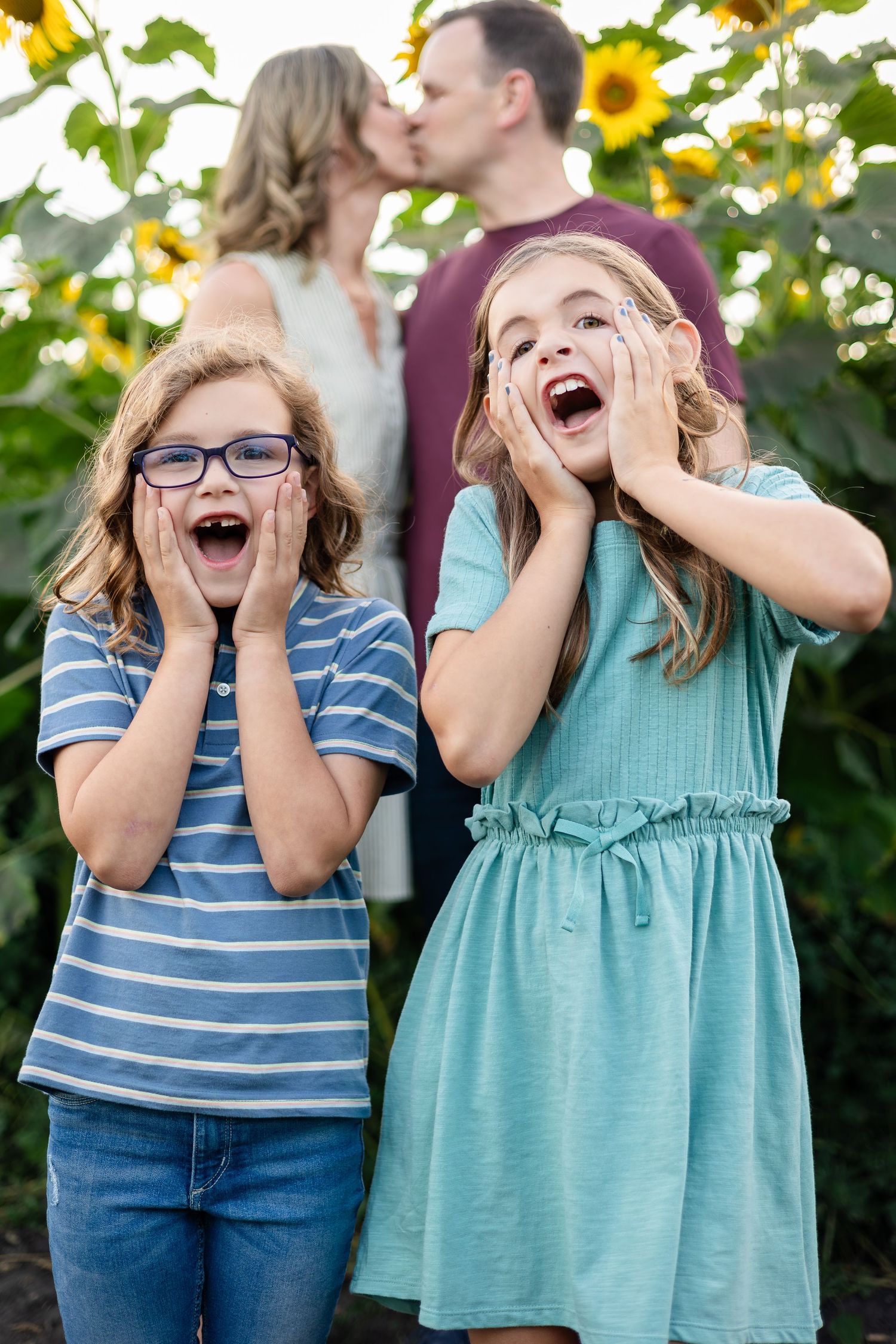 Children expressing excitement and surprise while posing in a sunflower field.