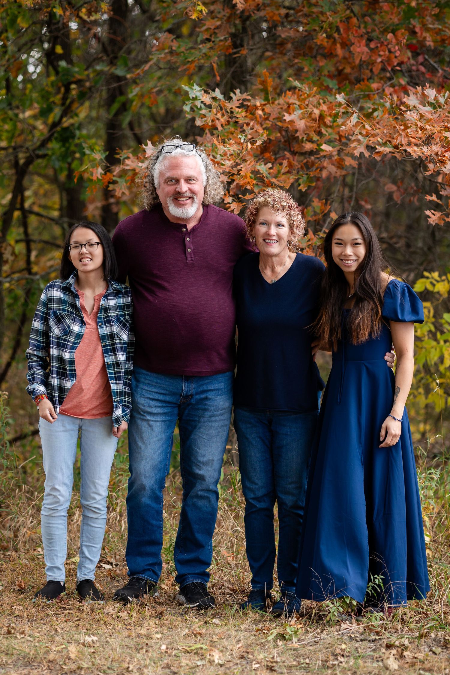 Extended family group portrait with coordinated navy and burgundy outfits in autumn setting.
