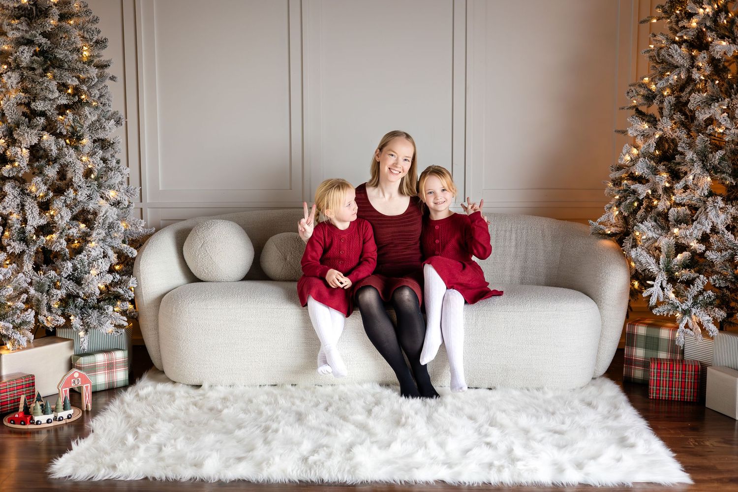 Holiday portraits of children on white couch with decorated Christmas tree in background.