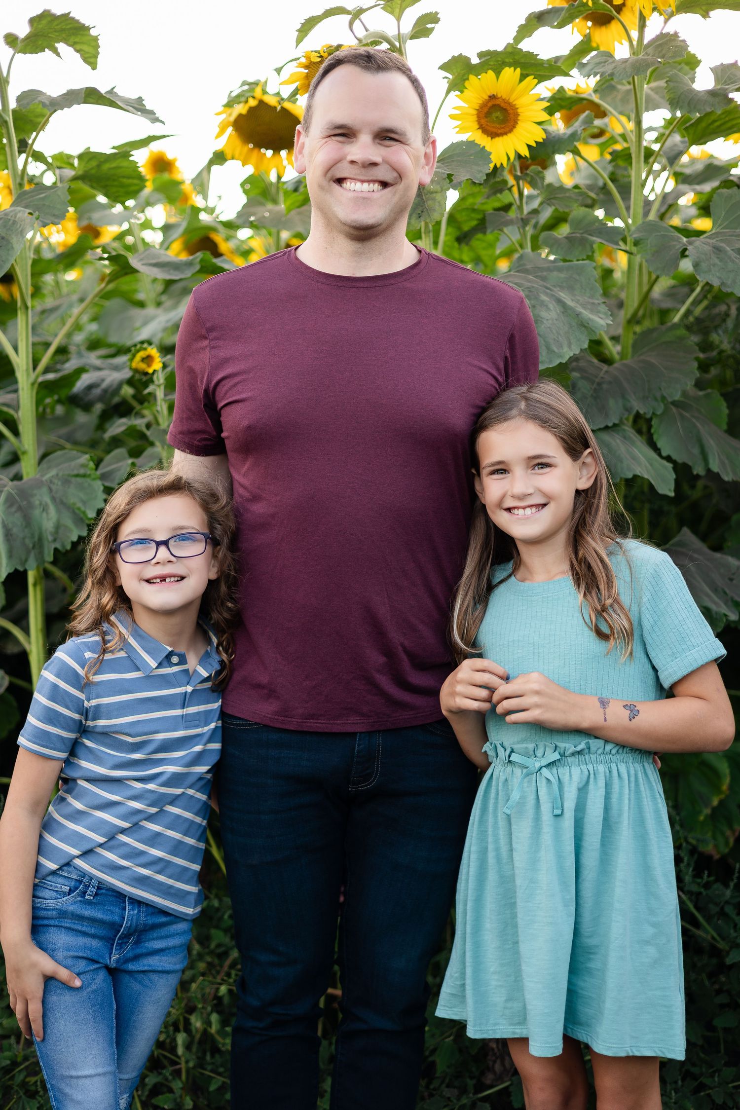 Cheerful family portrait against a backdrop of tall blooming sunflowers.