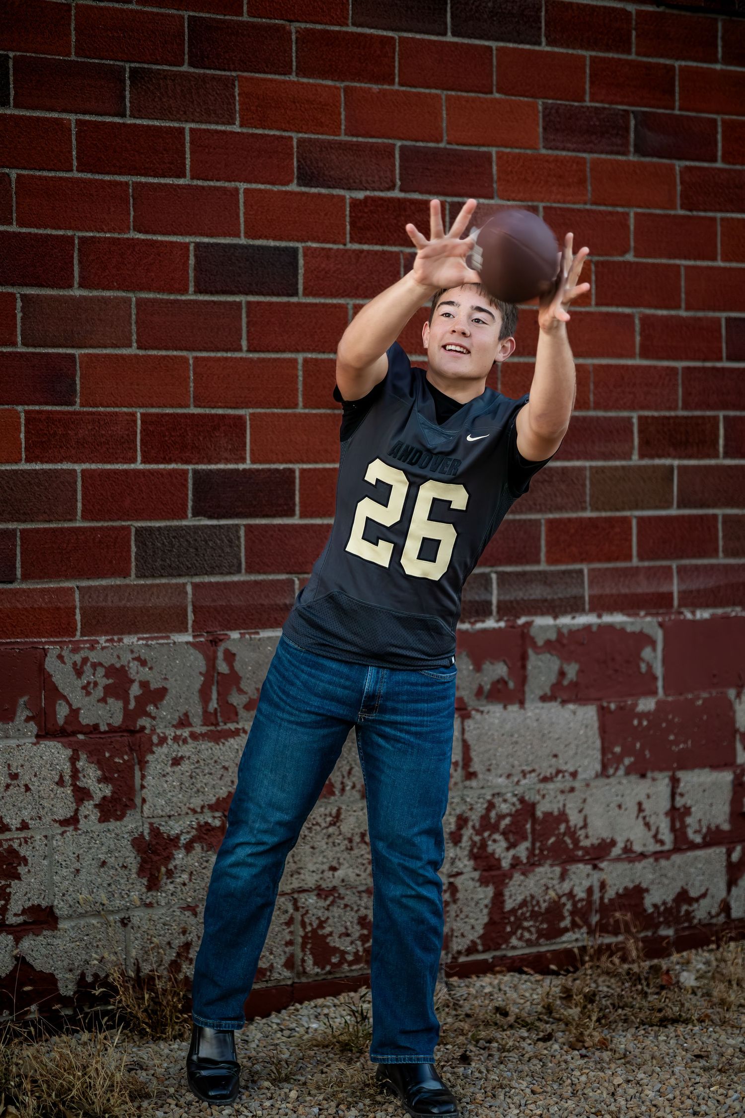 A person in black shirt and jeans poses playfully in front of a brick wall in a sequence of four action shots.