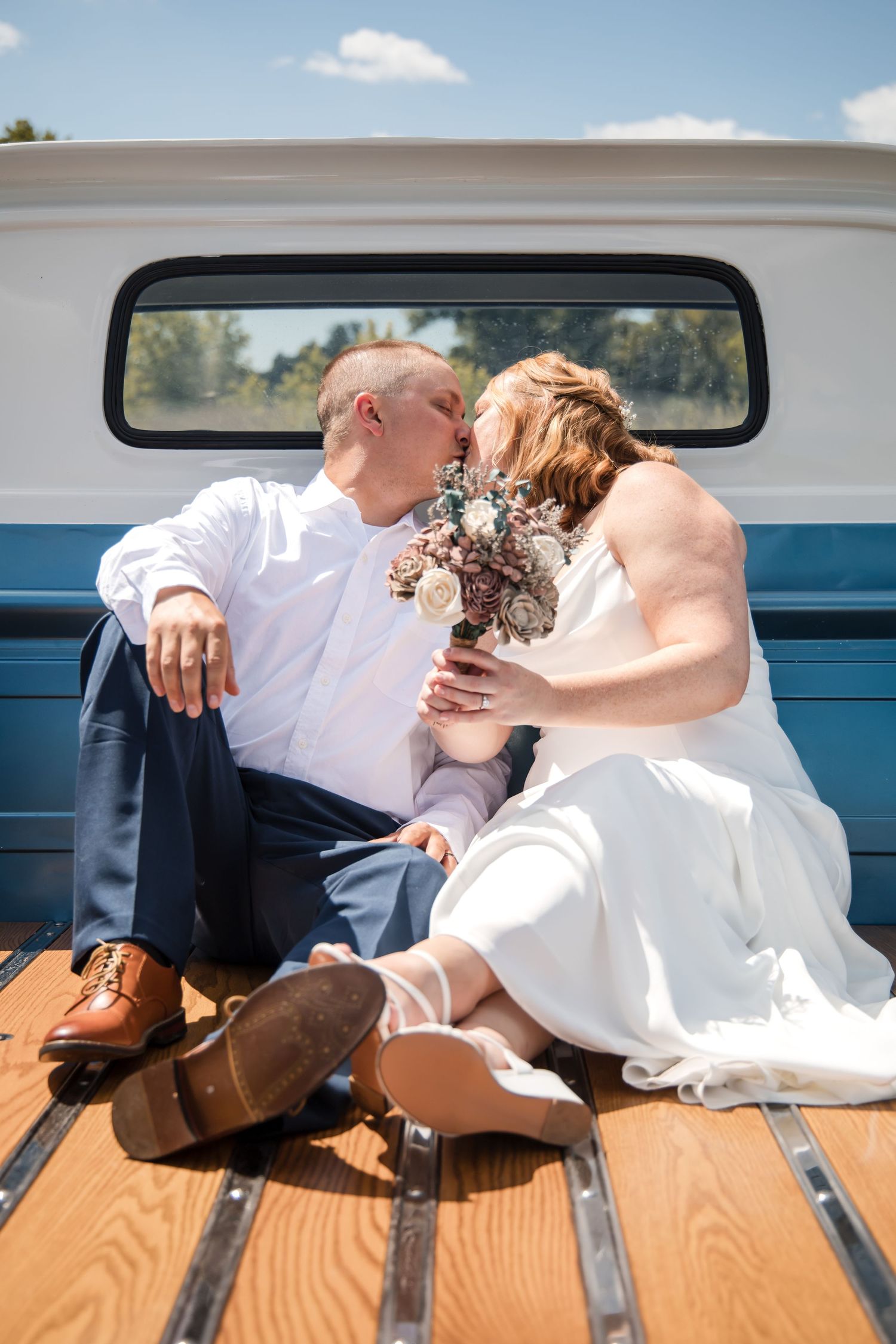 Couple sitting in the bed of a blue vintage truck during a wedding photoshoot.