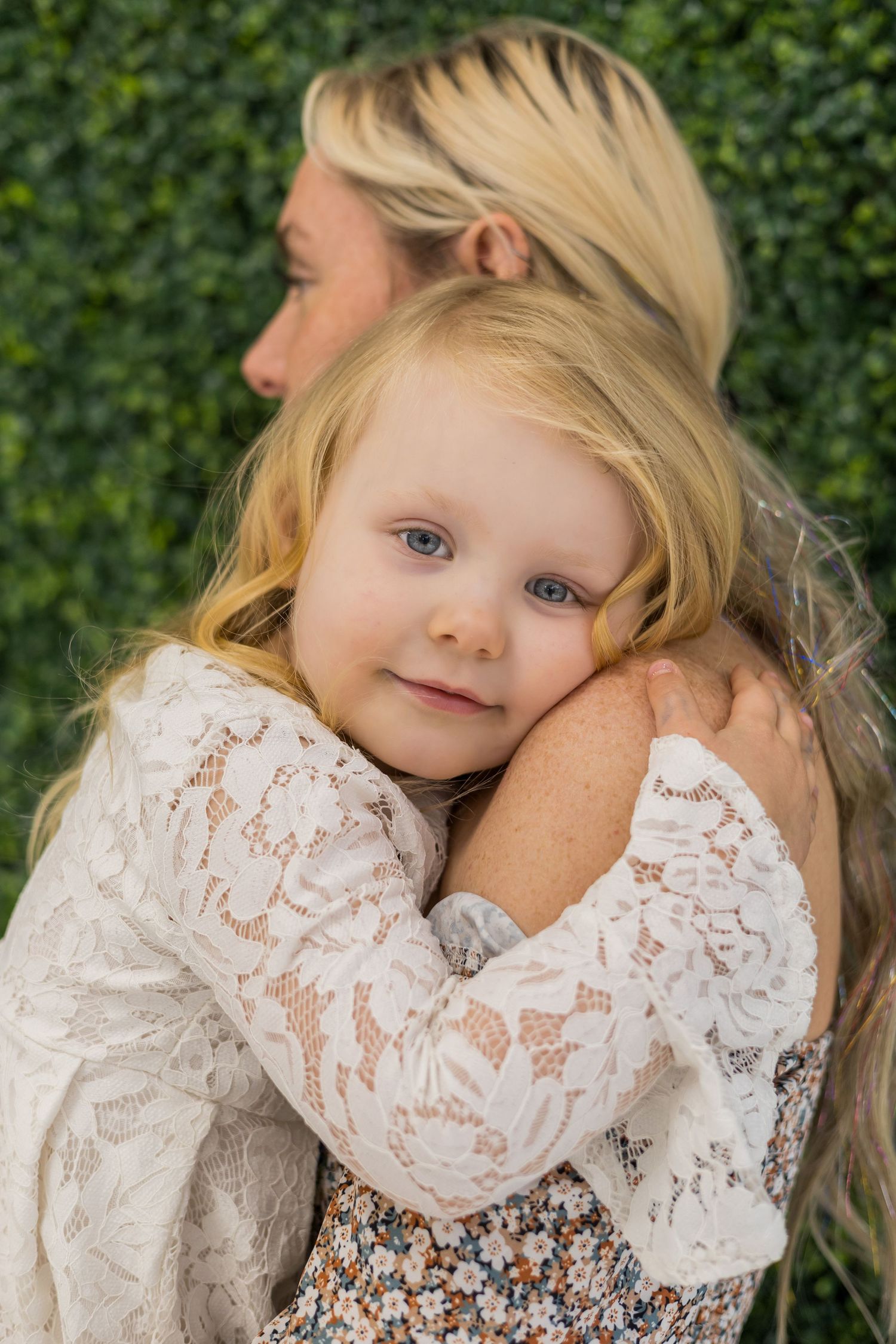A series of close-up portraits showing a young child in white lace against a green leafy background.
