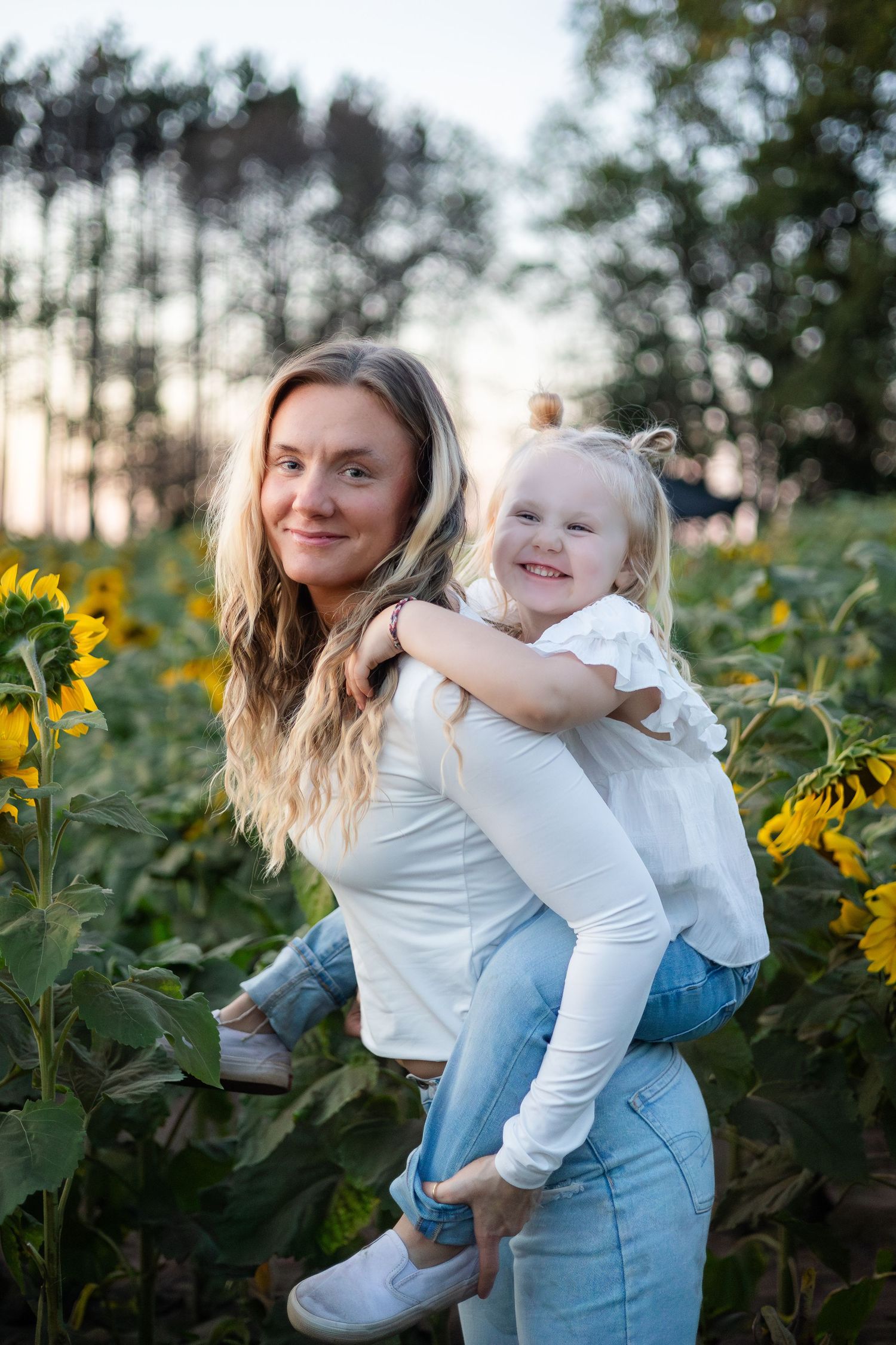 Two people share tender moments while posing in a sunflower field at sunset.