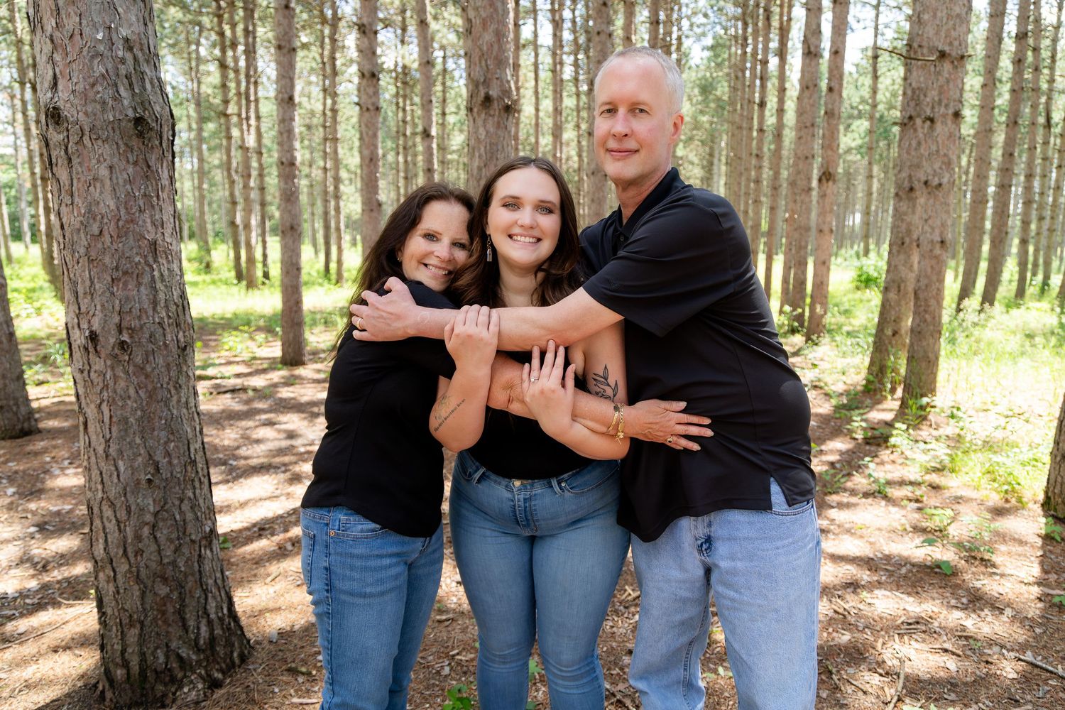 Family portrait session with multiple people posing together among tall pine trees.