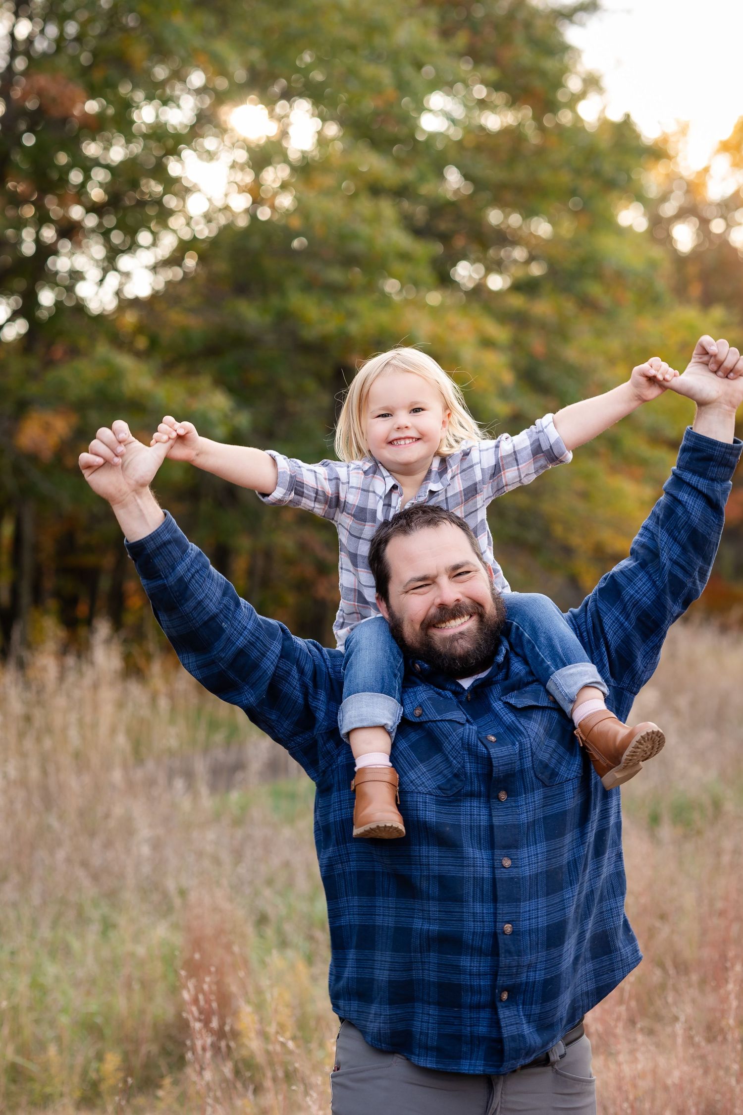 Joyful outdoor poses with arms raised against autumn foliage backdrop.