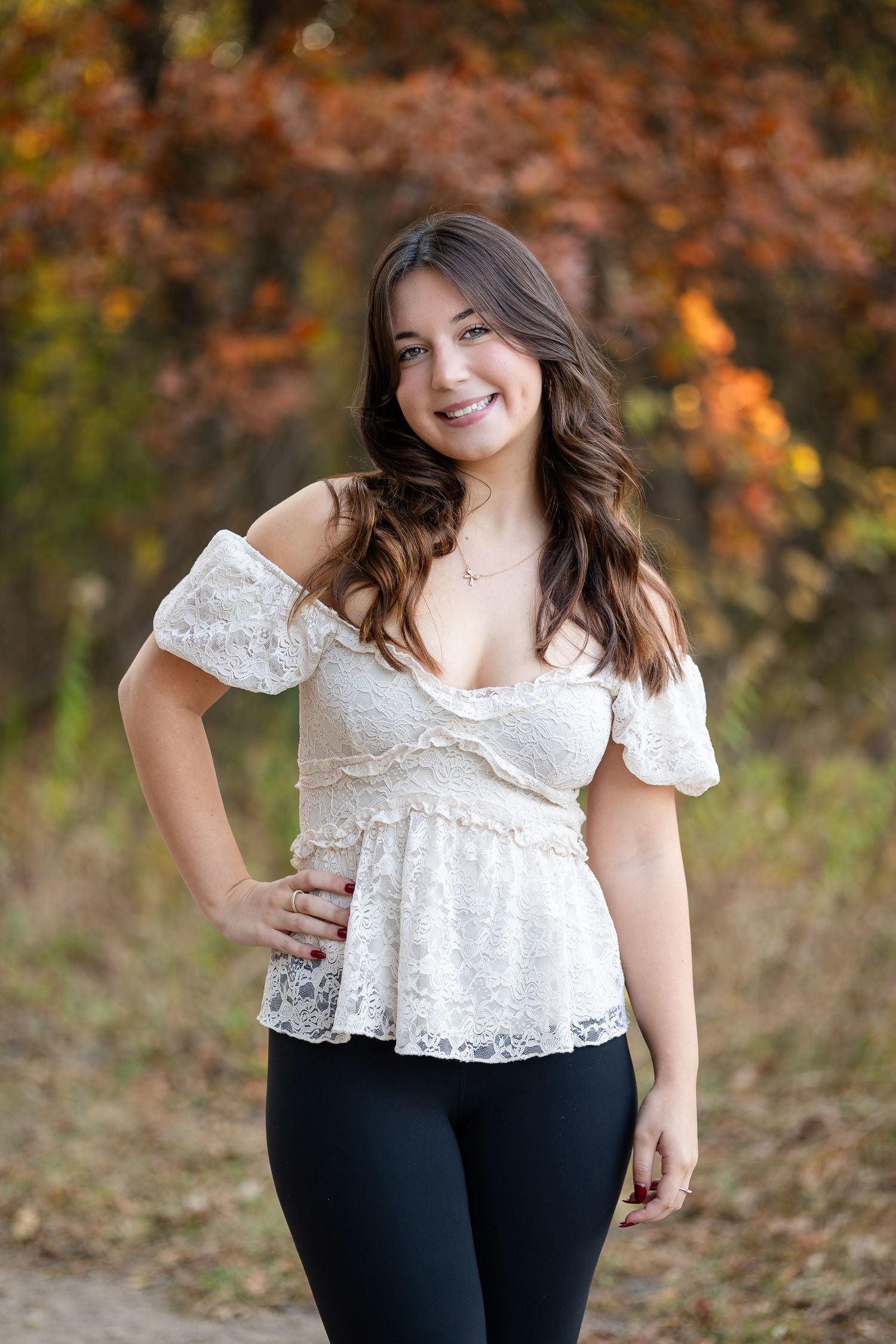 Outdoor photography in white lace top with autumn colors in background.