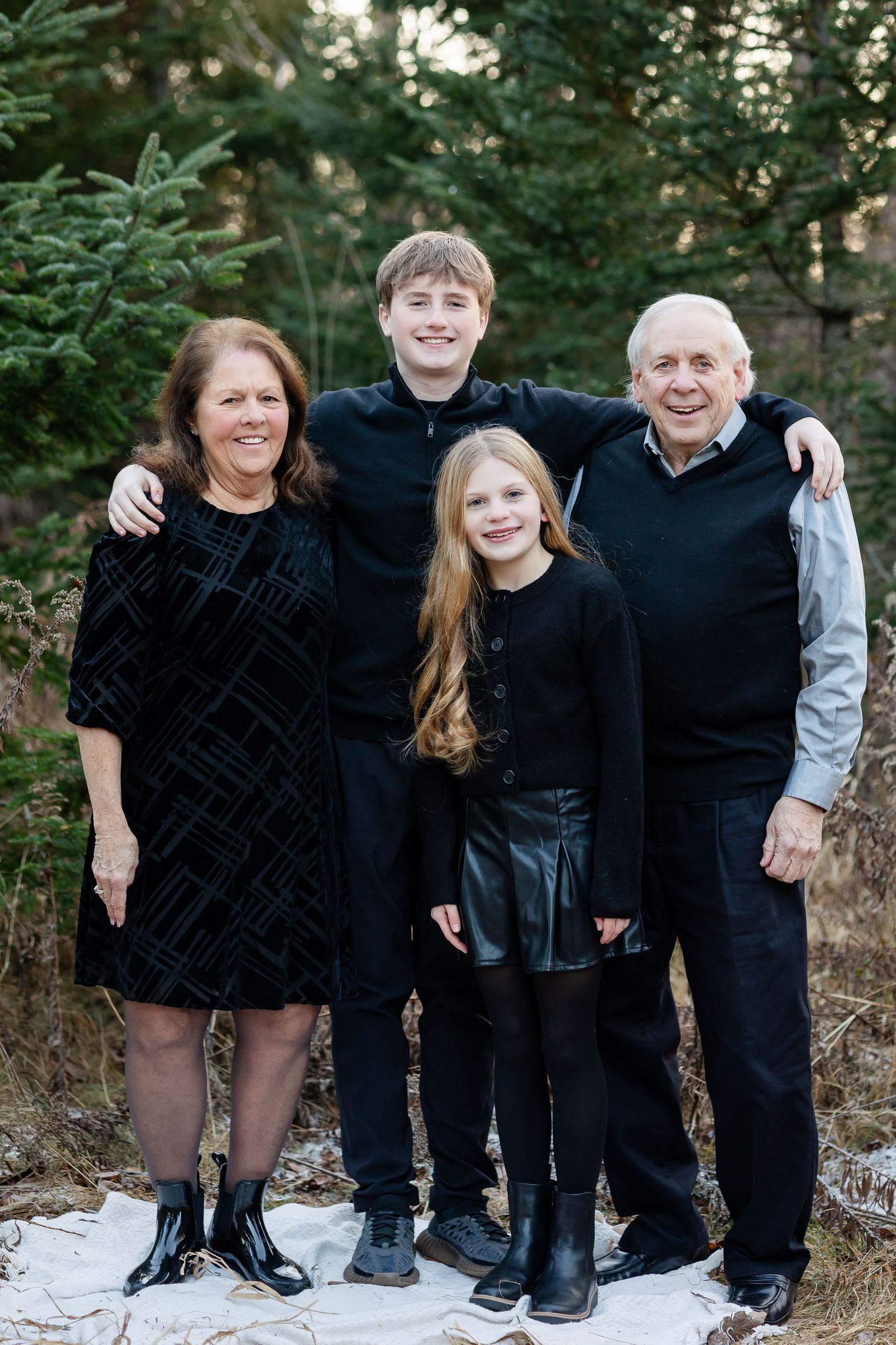Family members in coordinated black and grey outfits pose together in a forest setting.