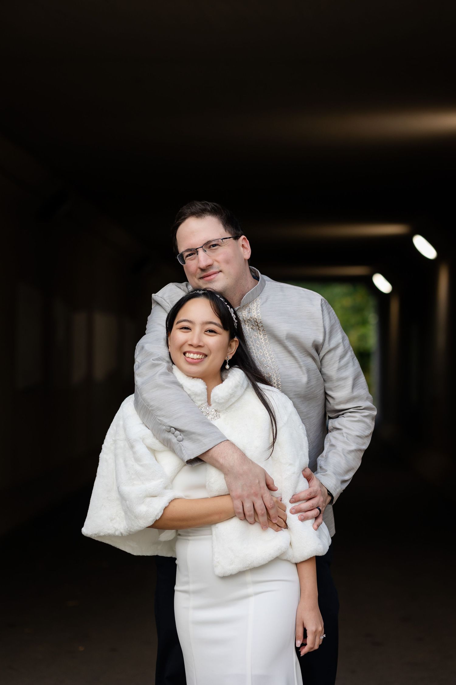 A couple shares an intimate moment while posing in a dark tunnel.