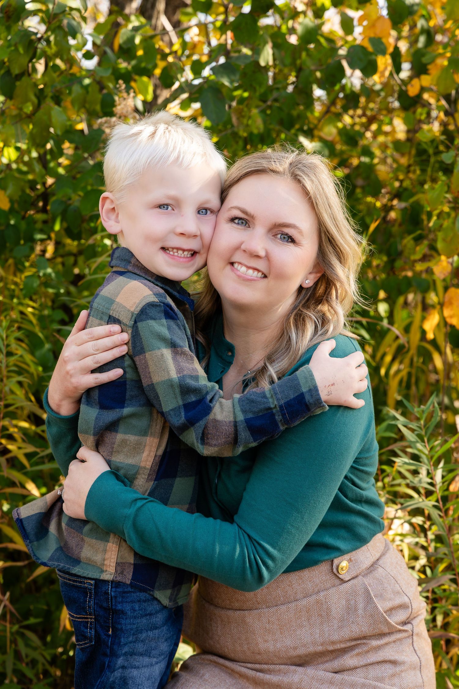 Tender family moment captured against autumn foliage background.