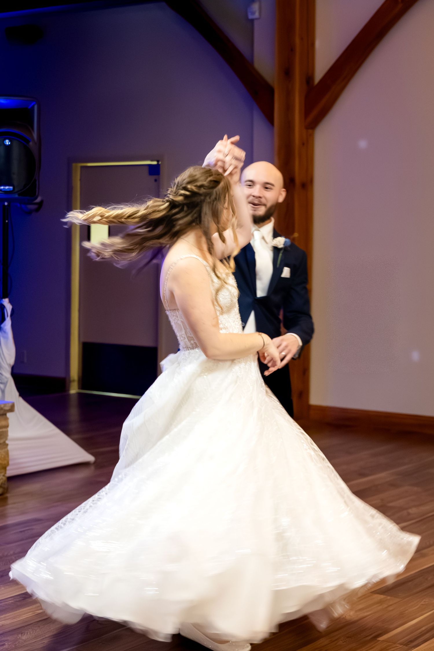 Bride twirls in her white gown as groom spins her during their joyful first dance.