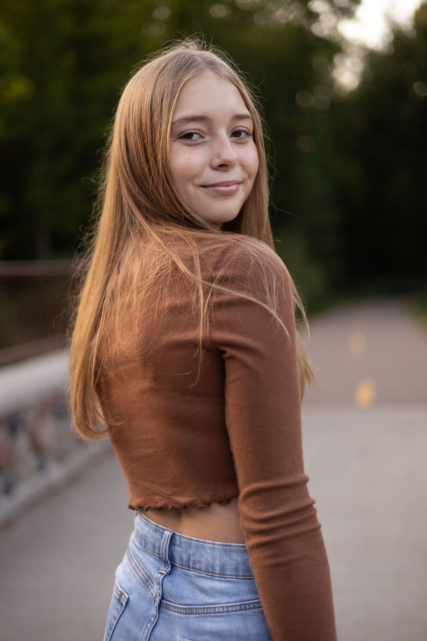 Casual portrait session on path with brown sweater and denim.