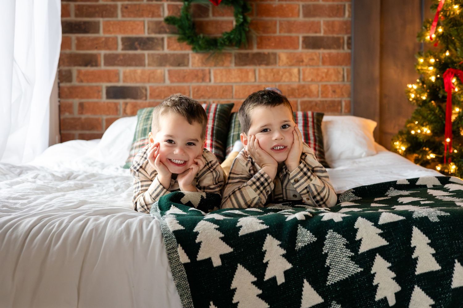 Holiday scene with brick wall, evergreen wreath, and white bedding.