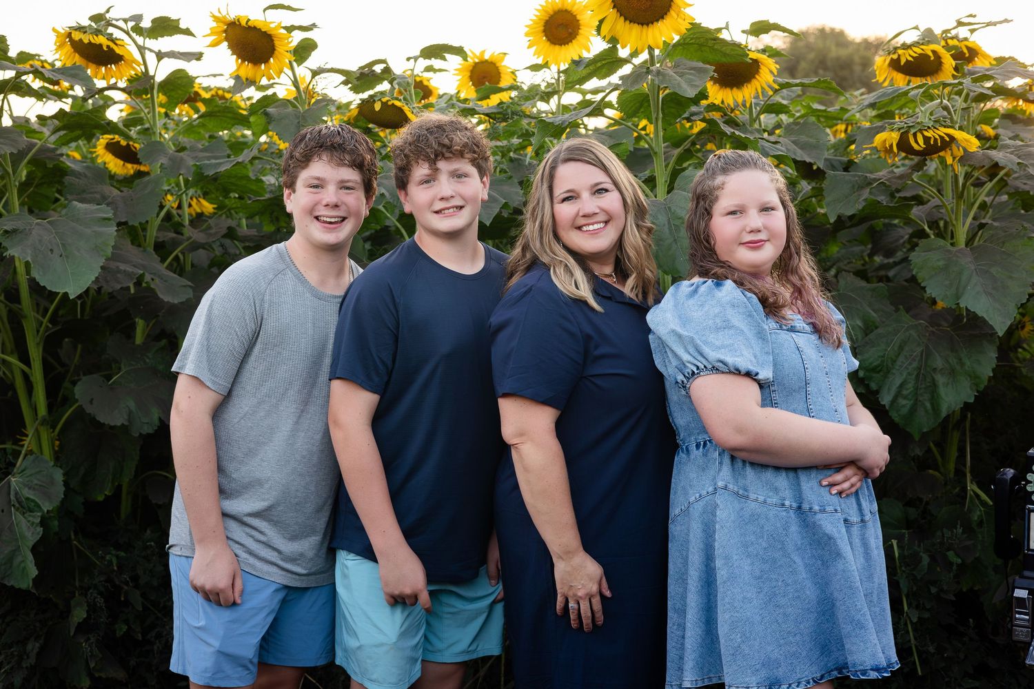Cheerful group photo in front of blooming sunflowers during sunset.