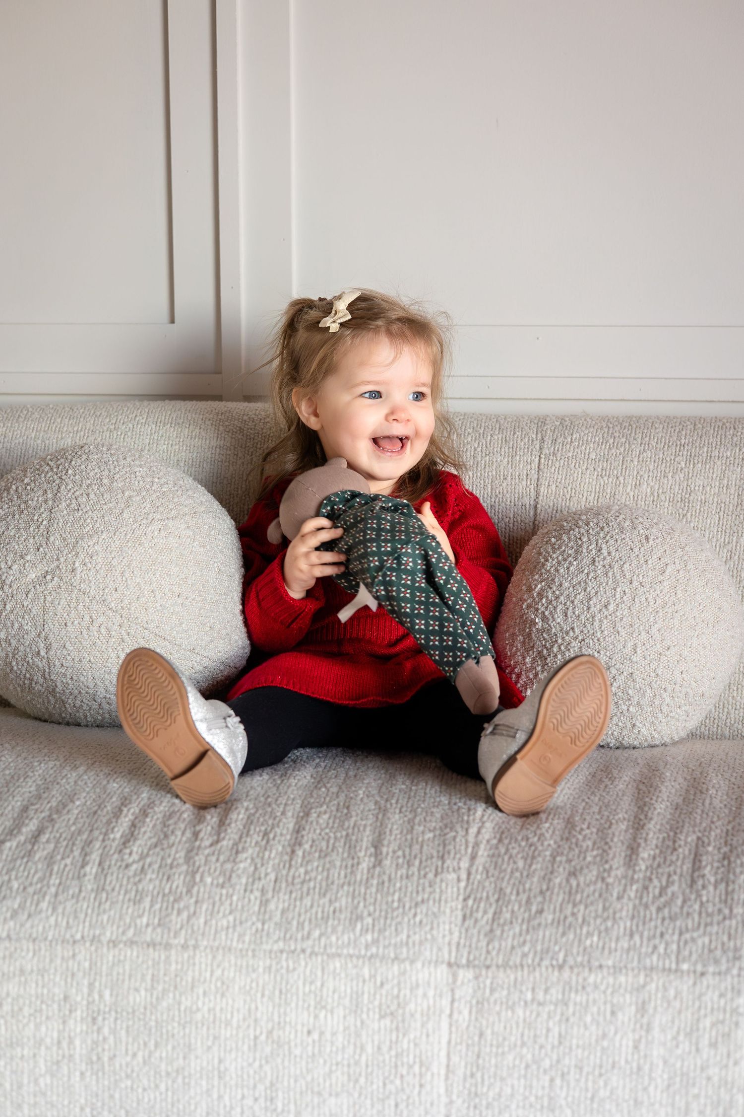Candid moments on a light gray couch wearing festive holiday attire.
