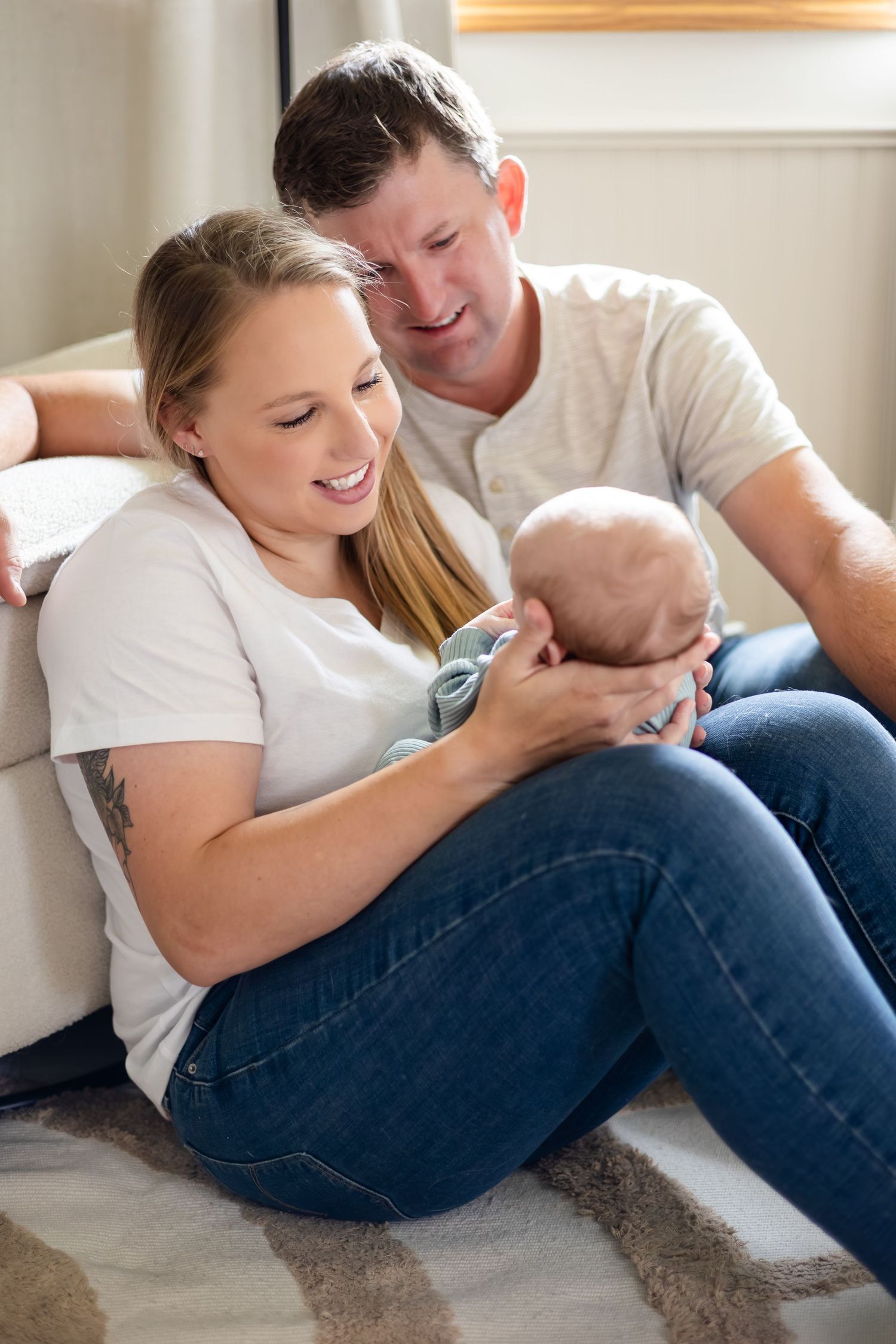 Family relaxing together on carpet while sharing loving moments with their baby.