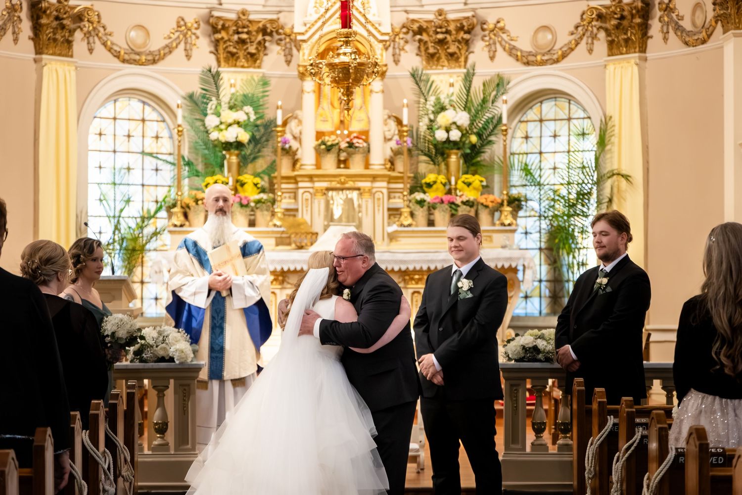 Bride and groom exchange vows at ornate church altar with priest officiating during elegant wedding ceremony.