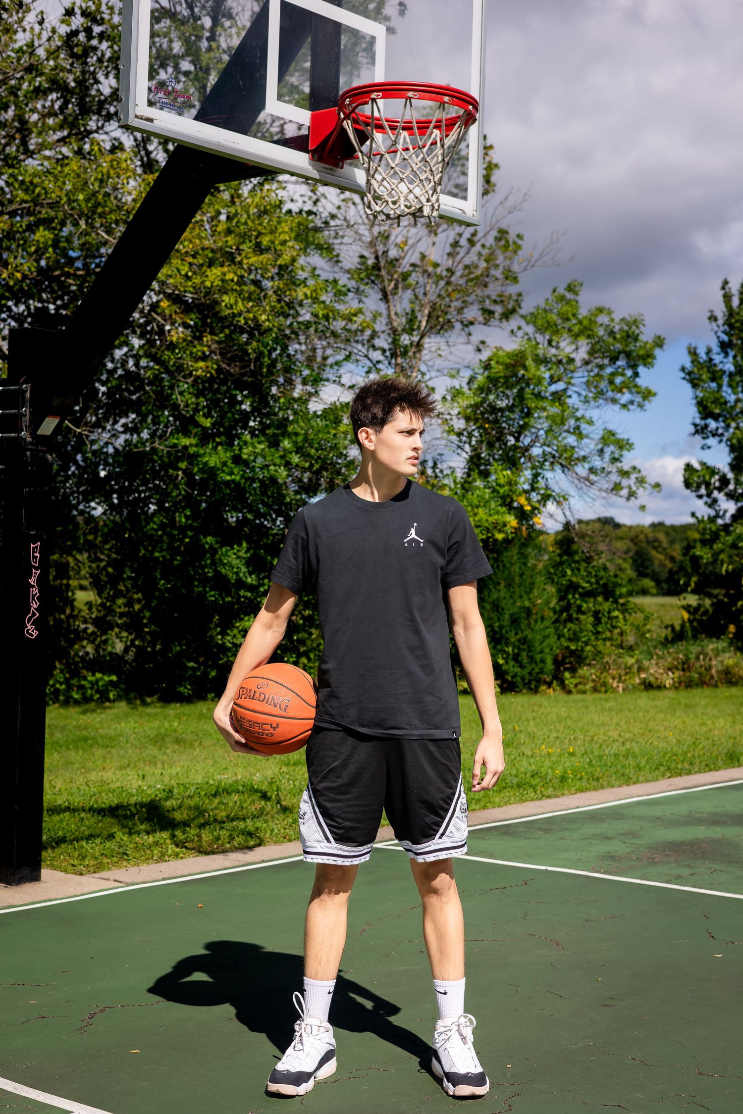 Player practicing basketball moves on outdoor green court.