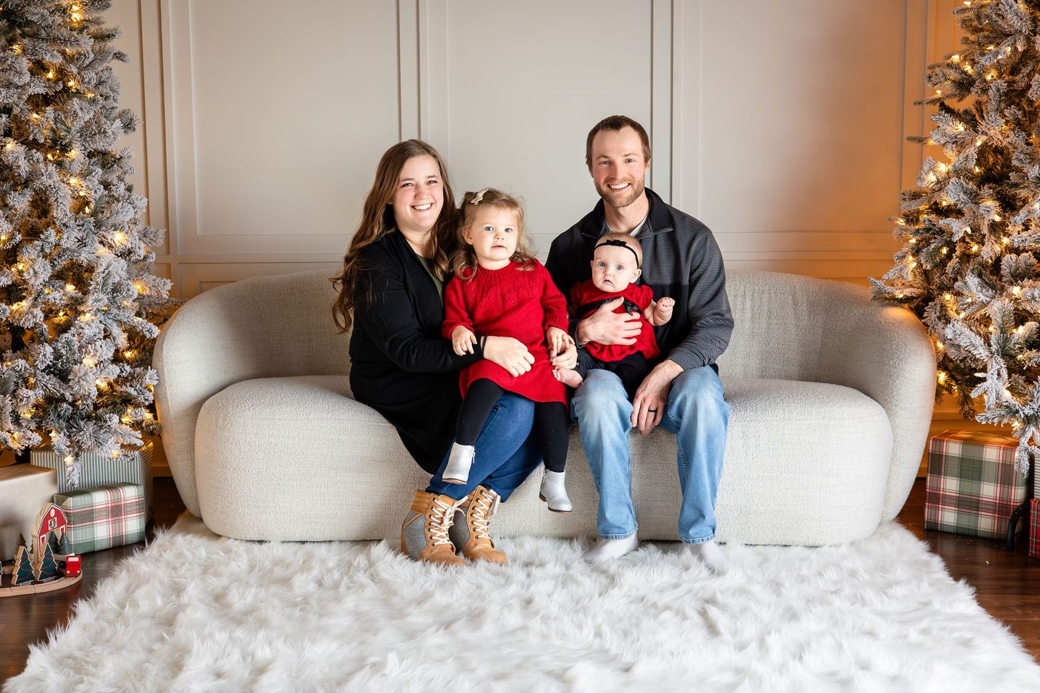 Family portrait session in front of a decorated Christmas tree and white couch.