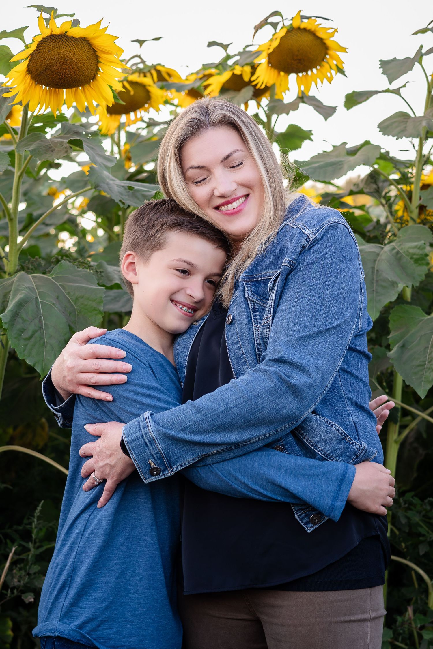 A touching family moment captured in a sunflower field with warm embraces and genuine smiles.
