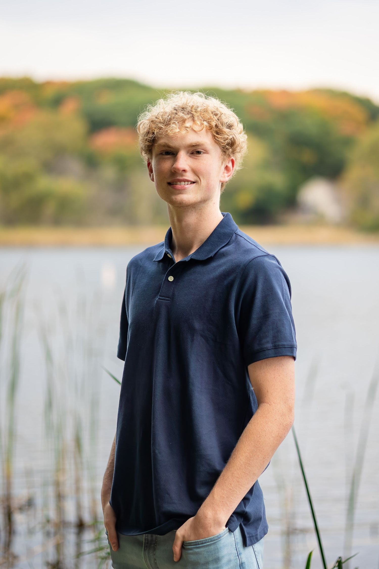 A series of outdoor portrait photos in navy blue attire against a lakeside backdrop with autumn foliage.