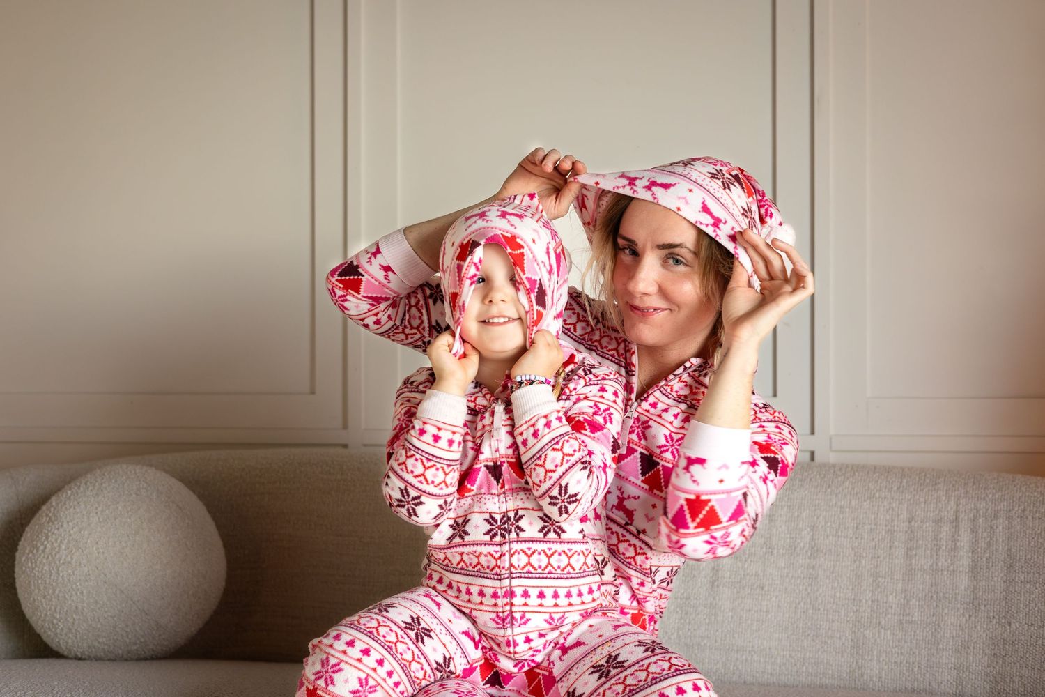 Family wearing red and white Nordic print pajamas sharing sweet moment on couch.