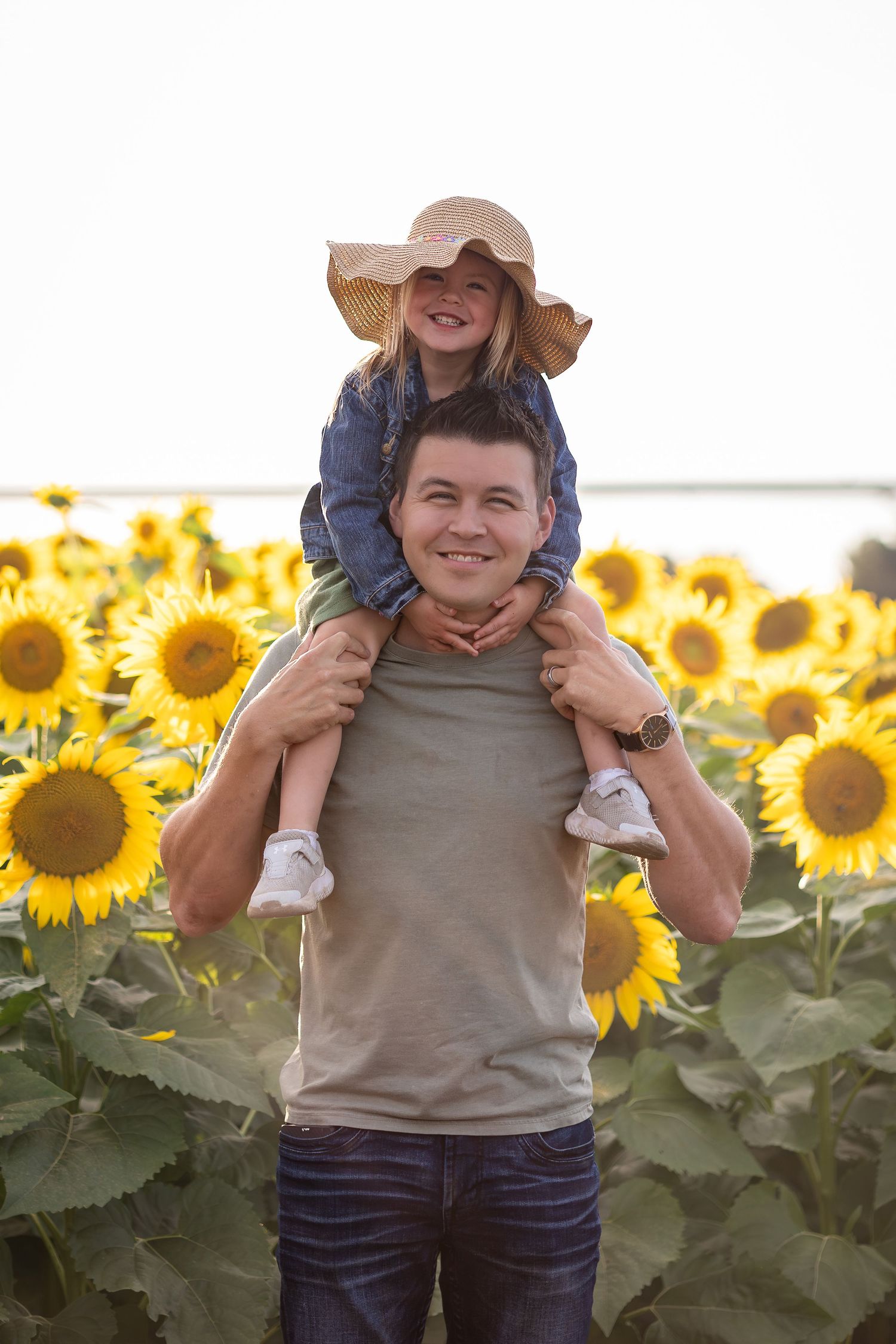 Family enjoying playful moments in a vibrant sunflower field during golden hour.