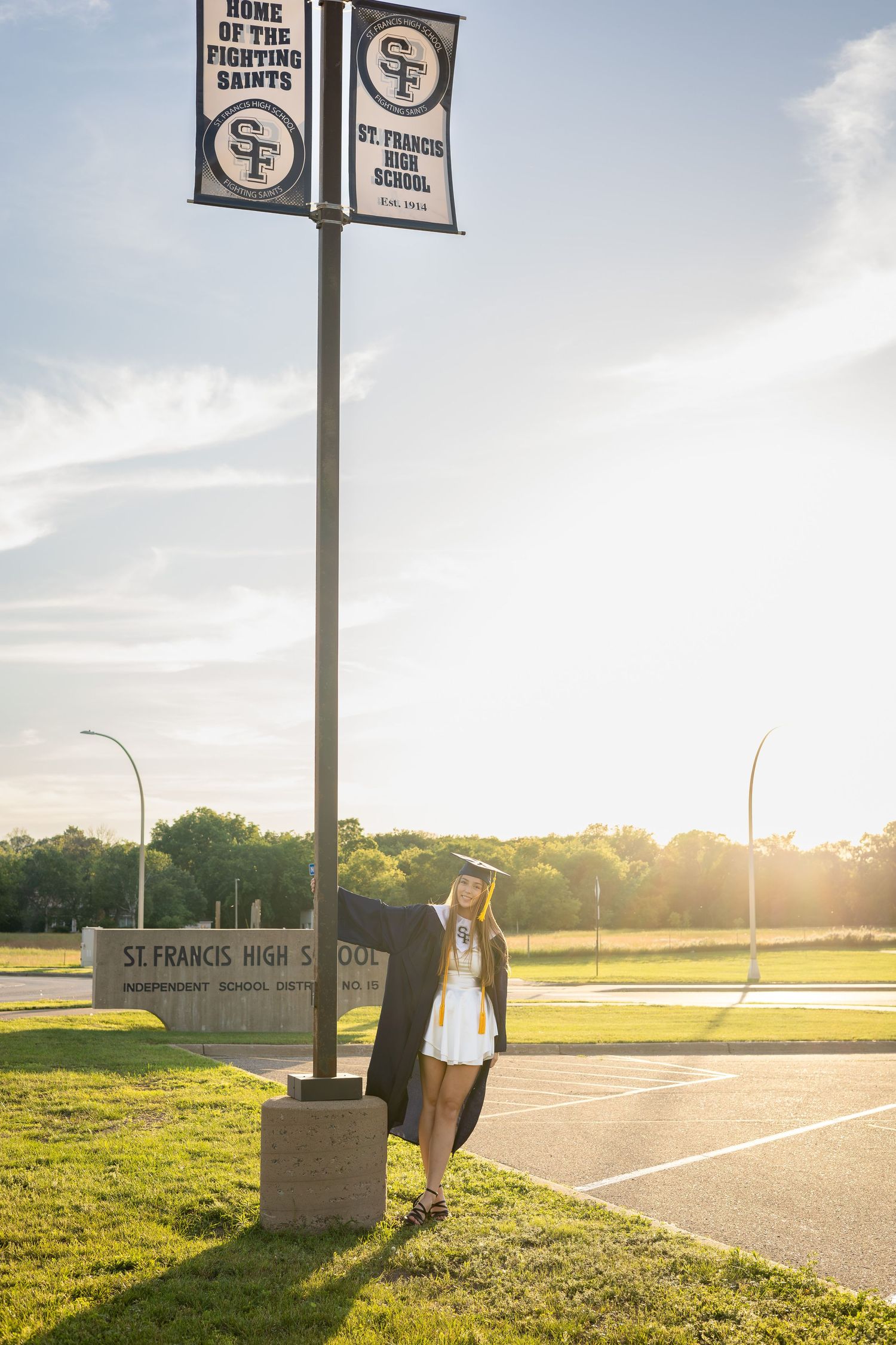 School sign and parking lot at sunset with golden light illuminating empty campus.