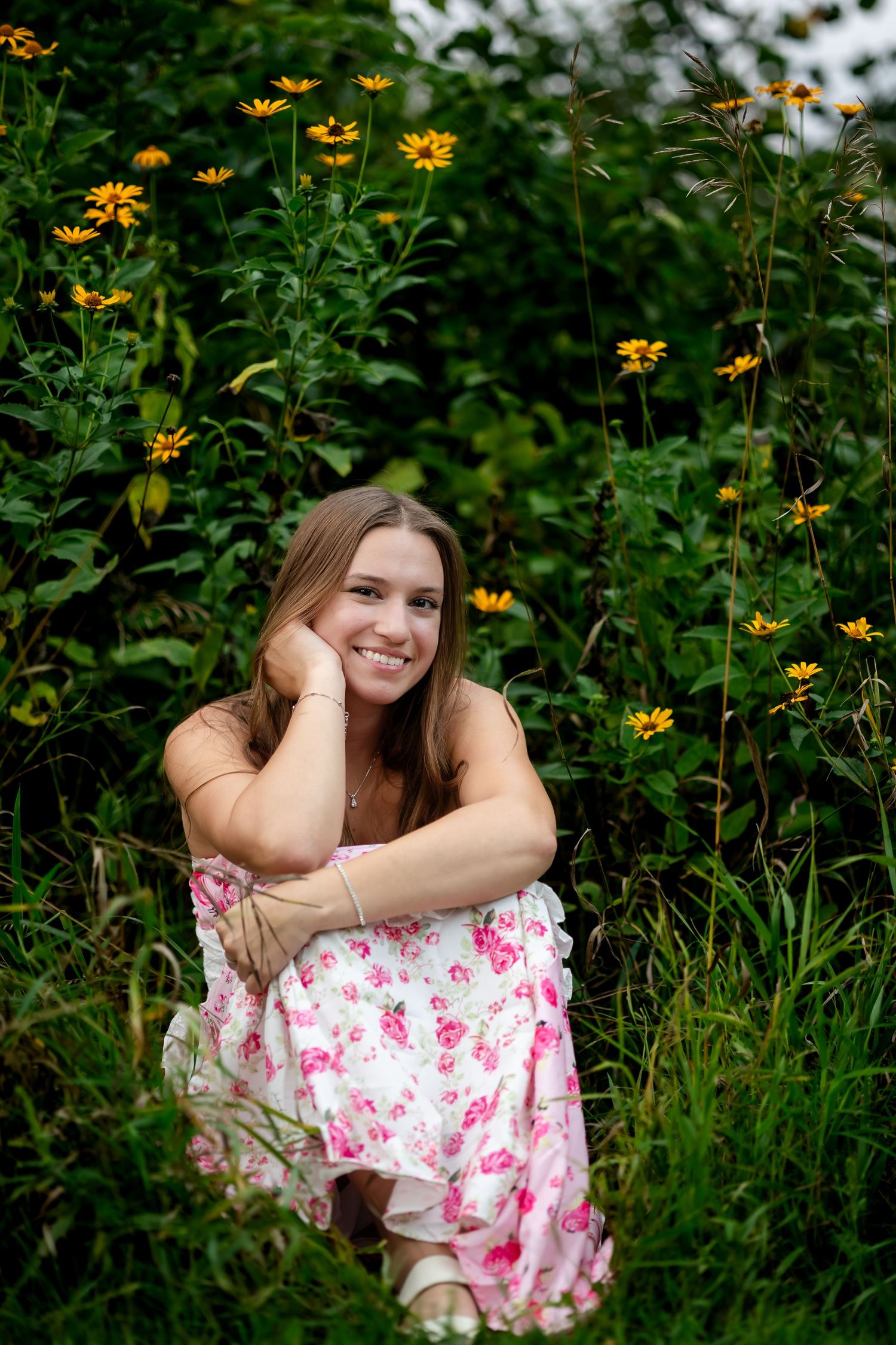Person in floral dress reclines among vibrant yellow flowers in natural setting.