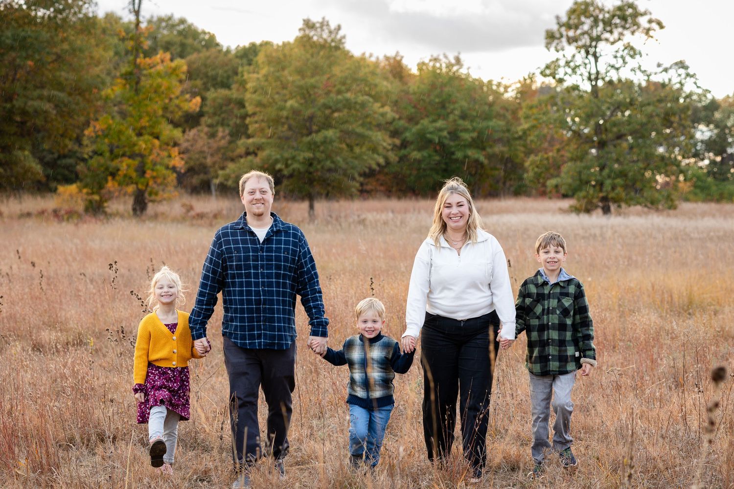 Group walking together through tall grass in autumn field.