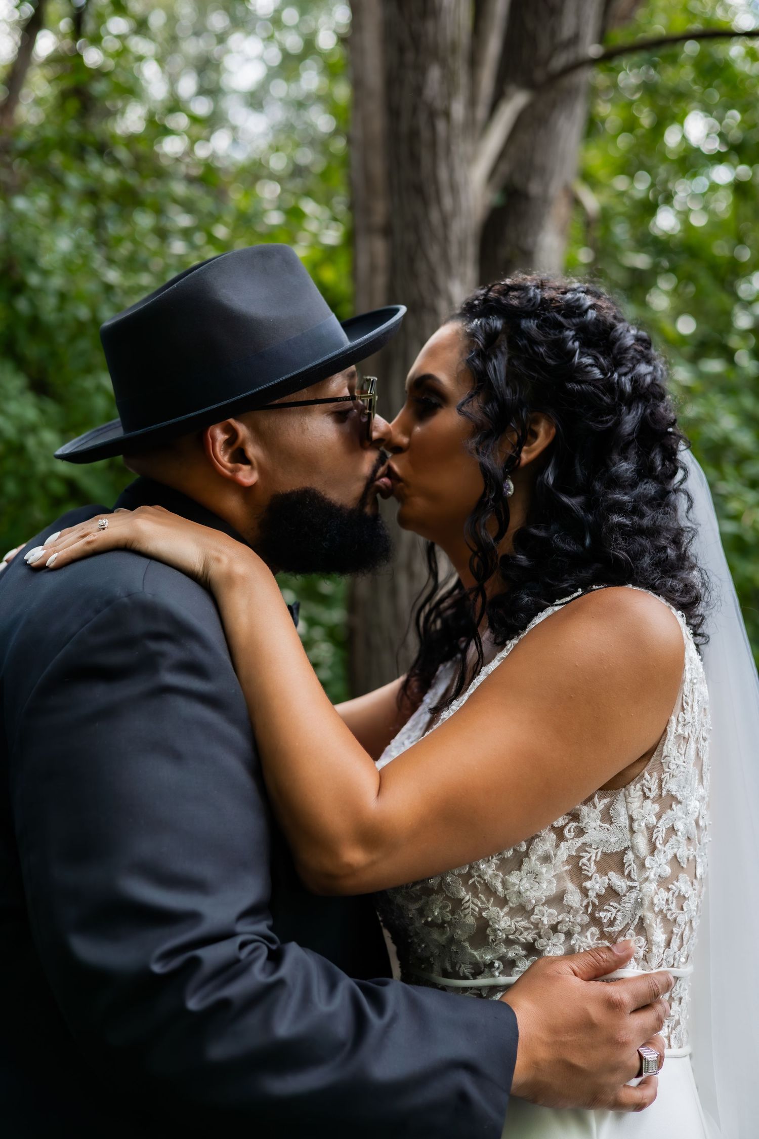 Wedding couple sharing intimate kisses in a wooded setting.