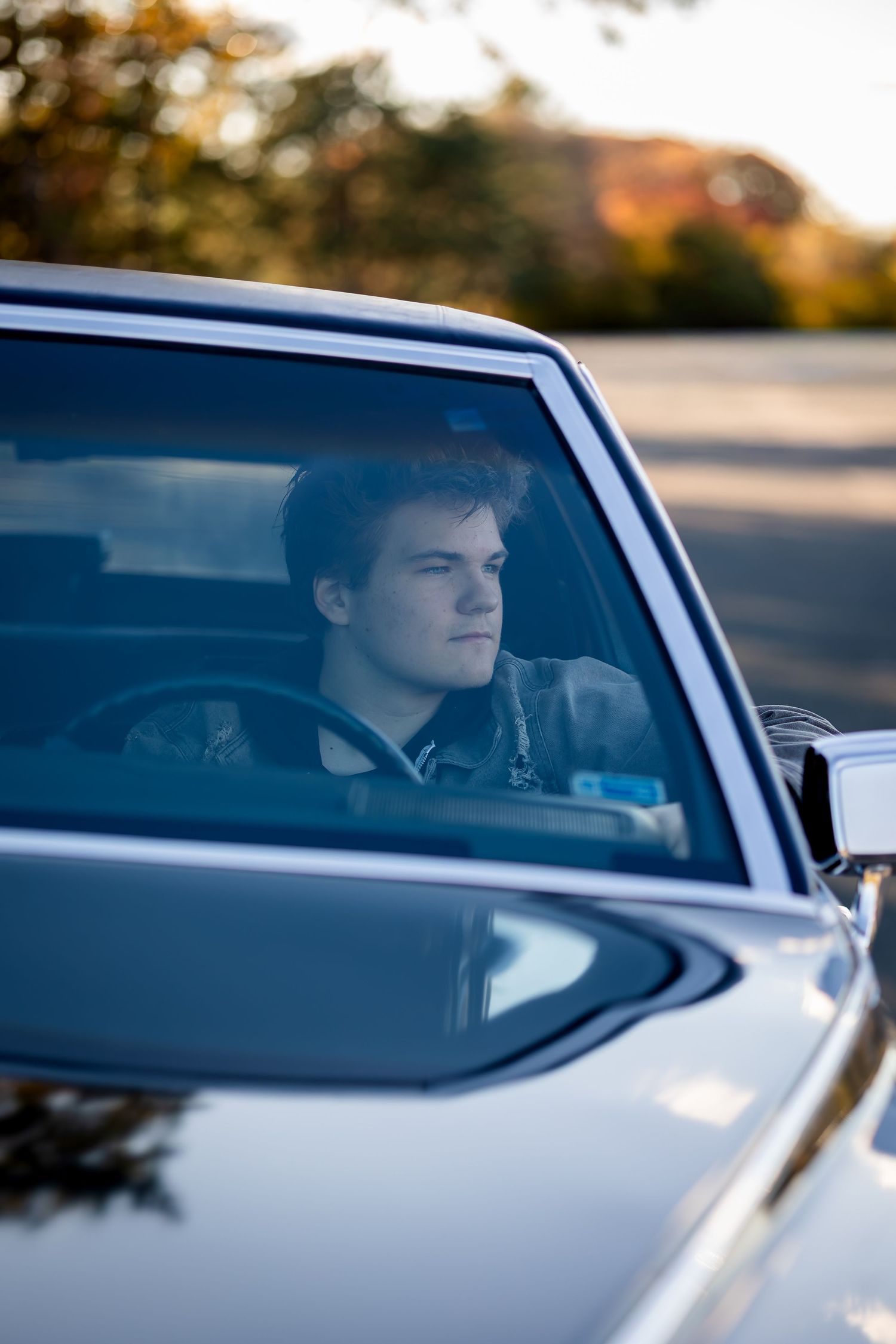 A driver is seen through the side windows of a car at sunset creating a cinematic composition.