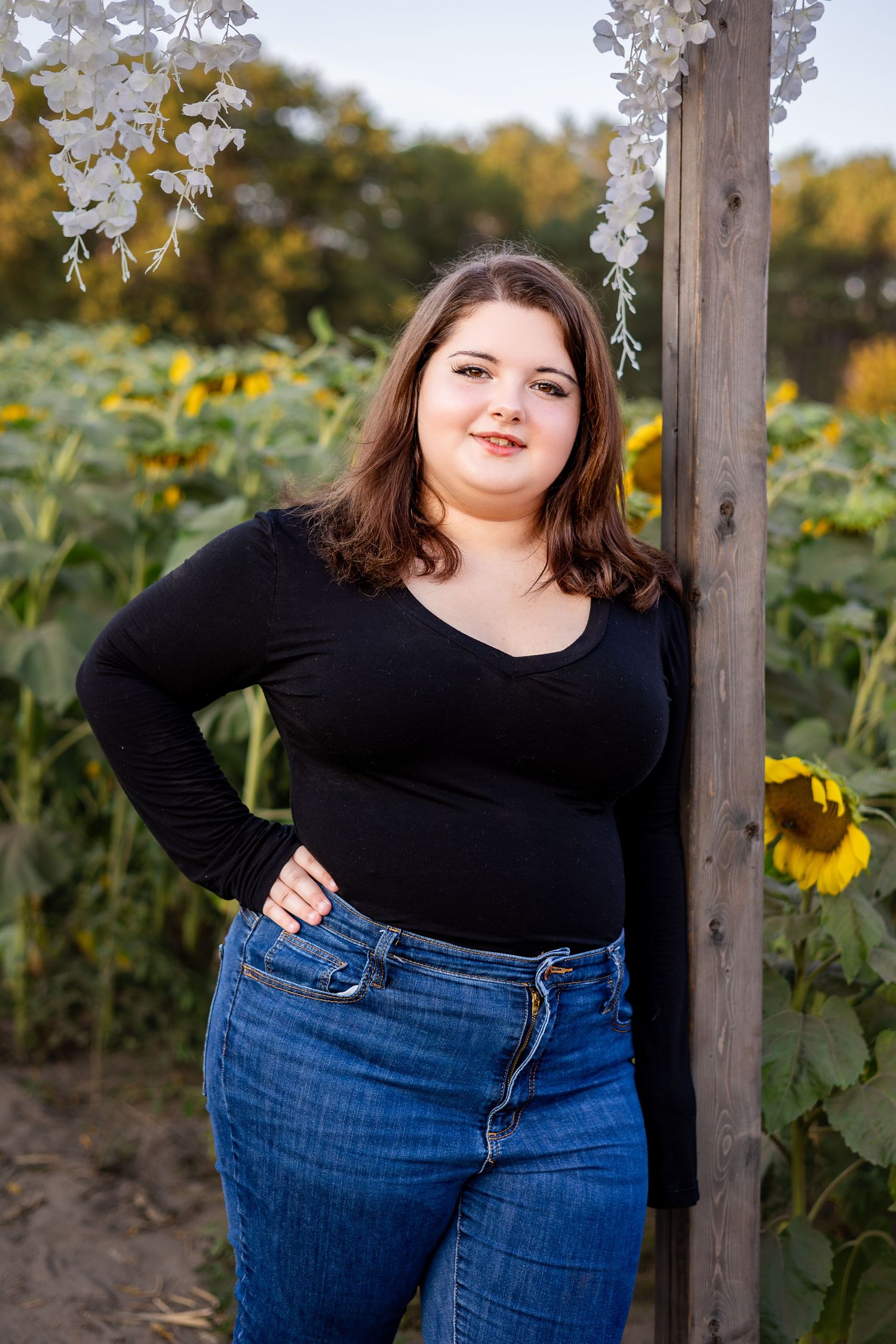 Rustic outdoor portrait session with wooden post and sunflowers in background.