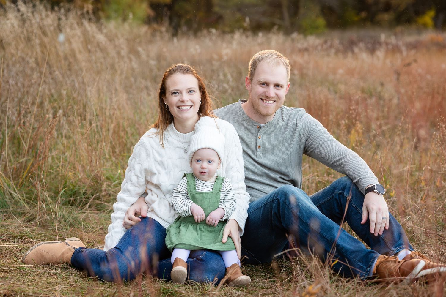 A casual family portrait sitting in tall grass during autumn.