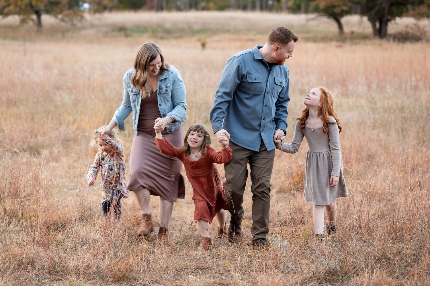 Family walking together through golden autumn field at sunset.