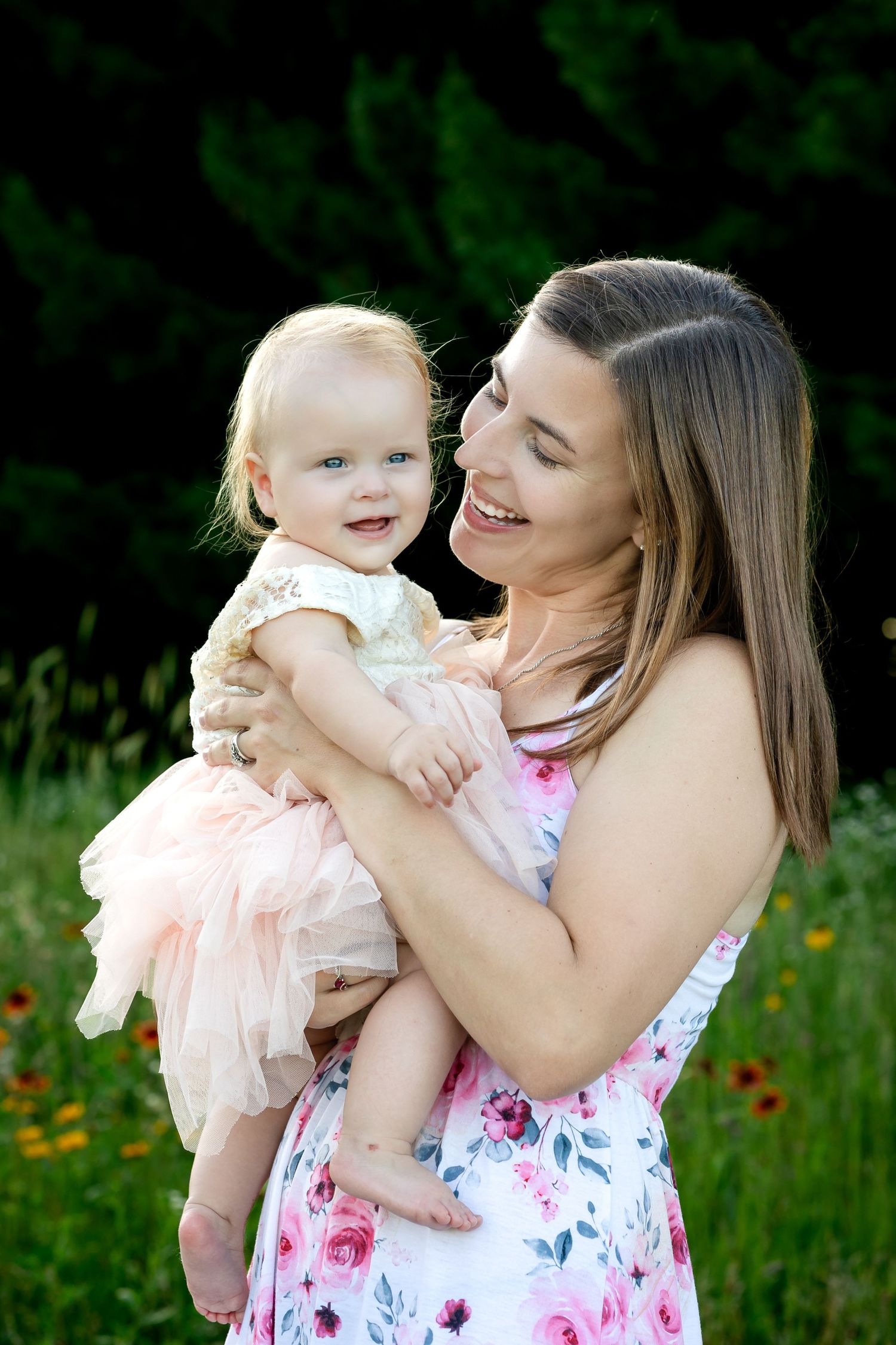 Parent and baby share tender moment in blooming wildflower field.