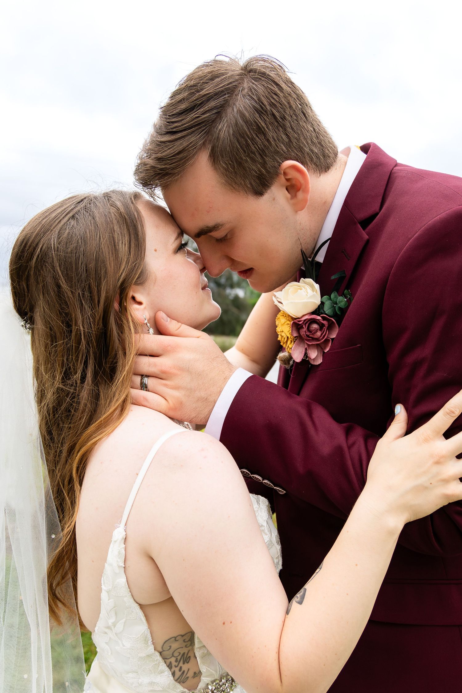 Romantic wedding portrait with couple sharing intimate moment outdoors.