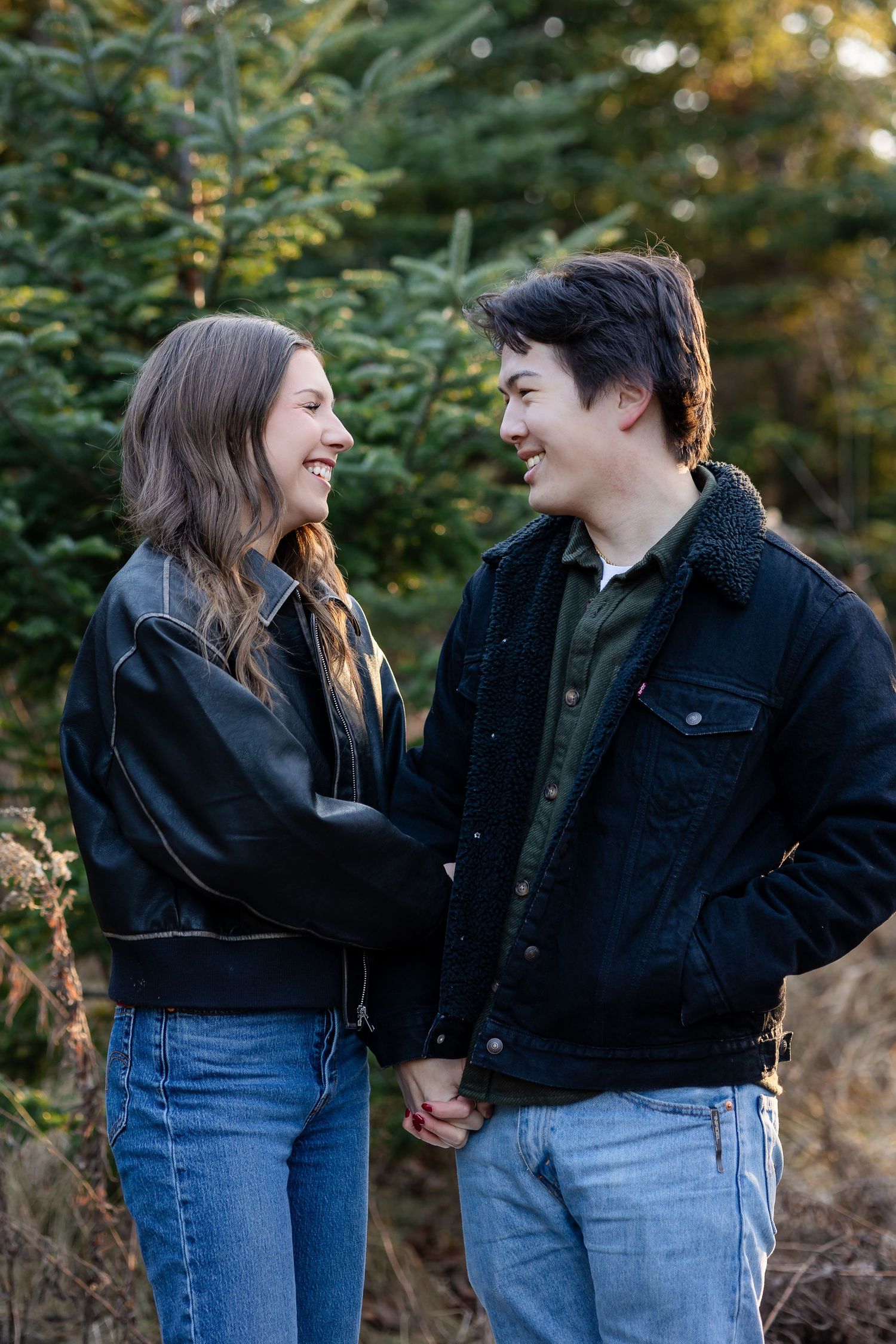 Two people share joyful laughter while wearing matching denim and dark jackets.