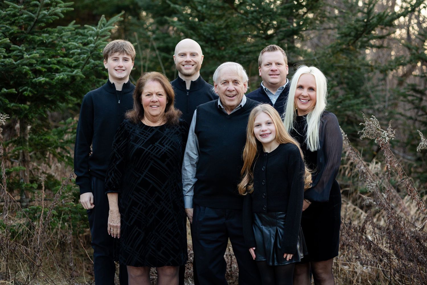 Group photo of family members wearing black attire against natural outdoor backdrop.