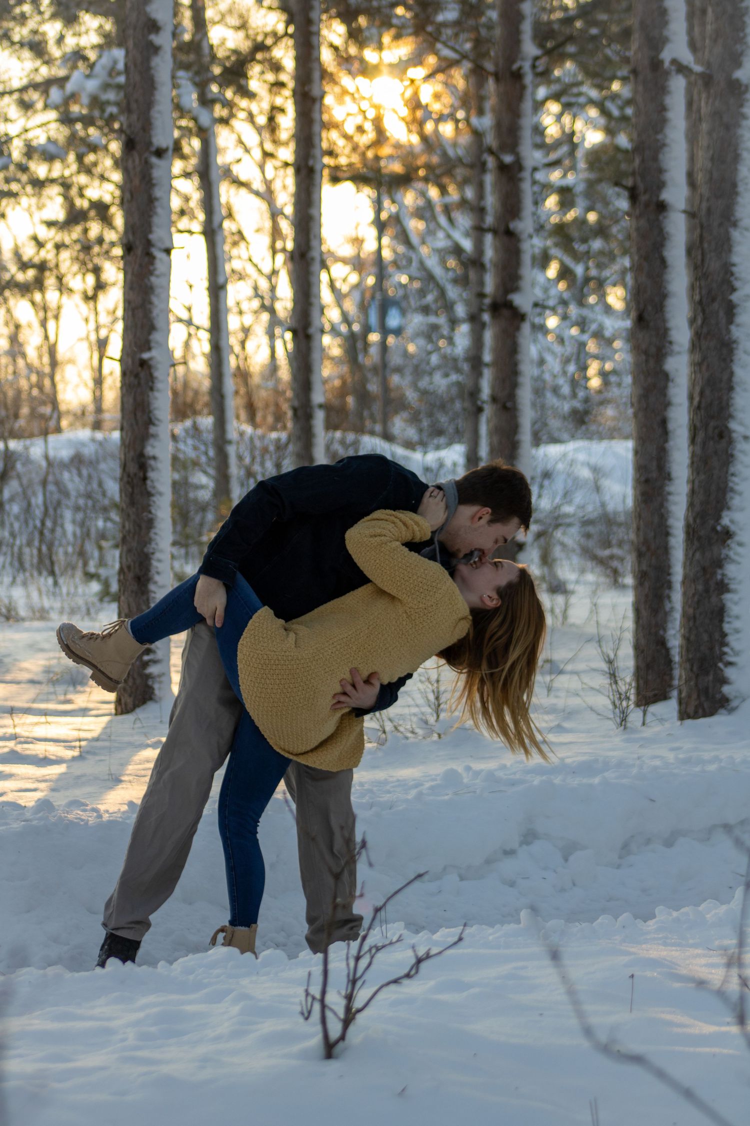 A sequence showing a couple performing a romantic dance dip in the snowy woods at sunset.